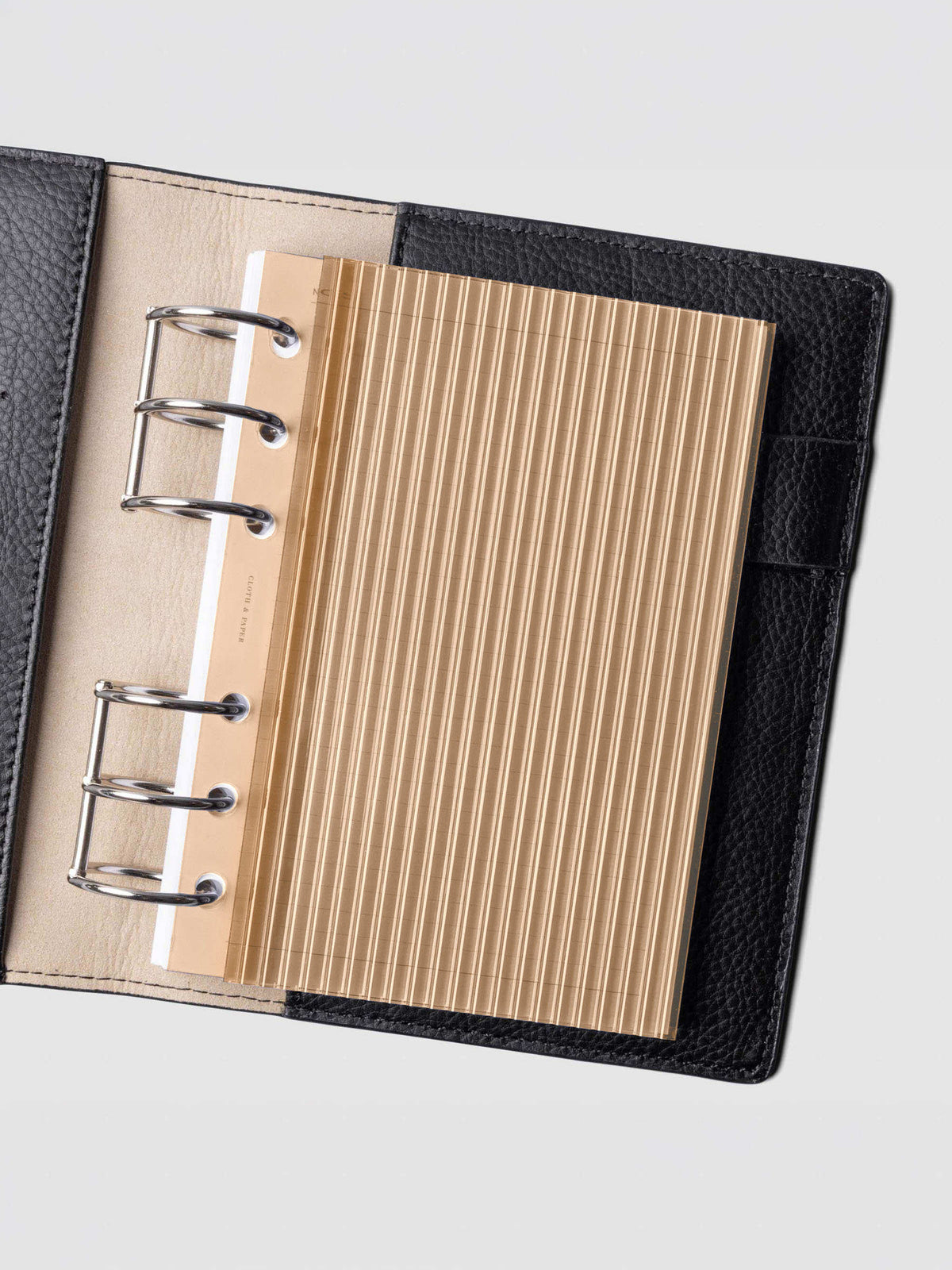 Bisque fluted planner dashboard in A6 size shown in a black leather six ring agenda with silver rings.