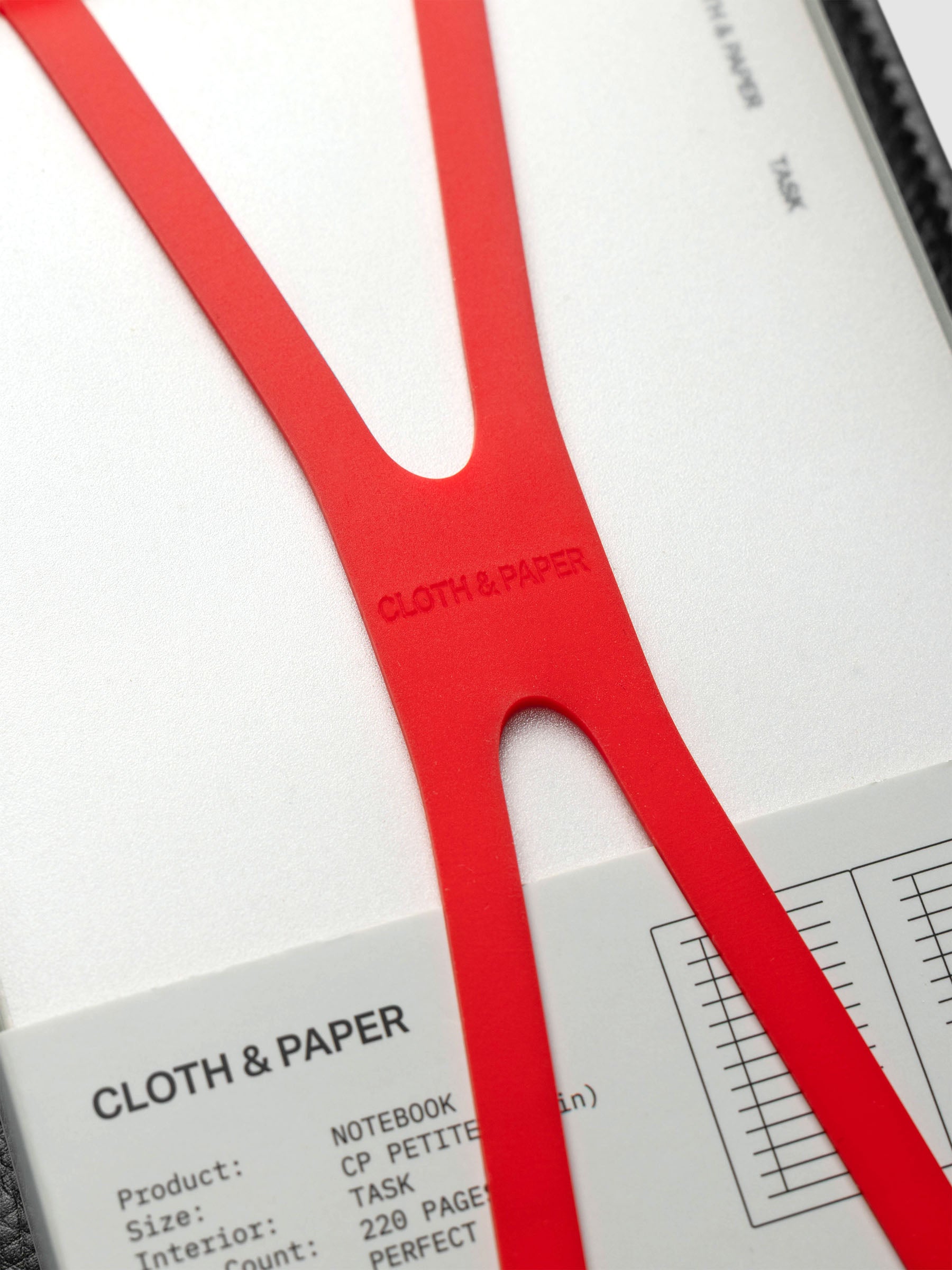 Close up of the red planner closure band with Cloth & Paper imprint on center.
