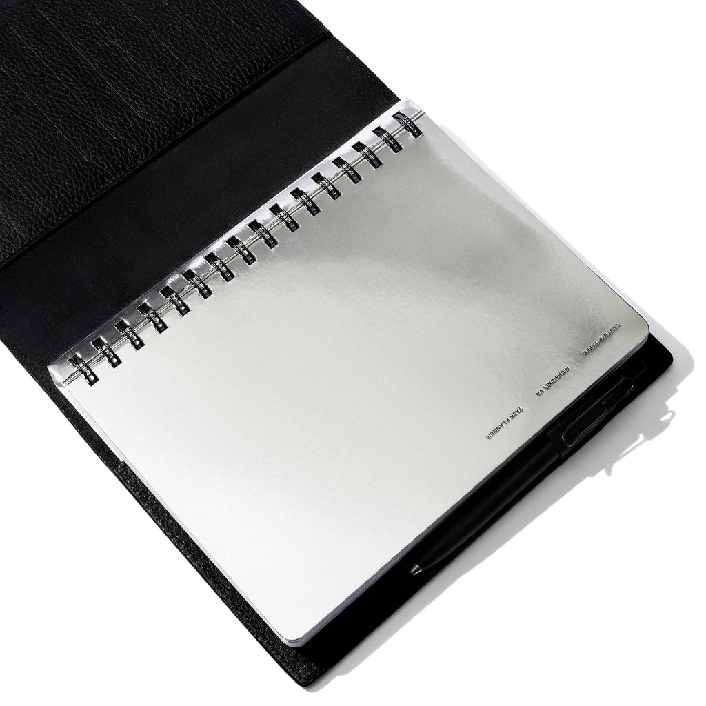 Silver notebook displayed in a black leather folio.