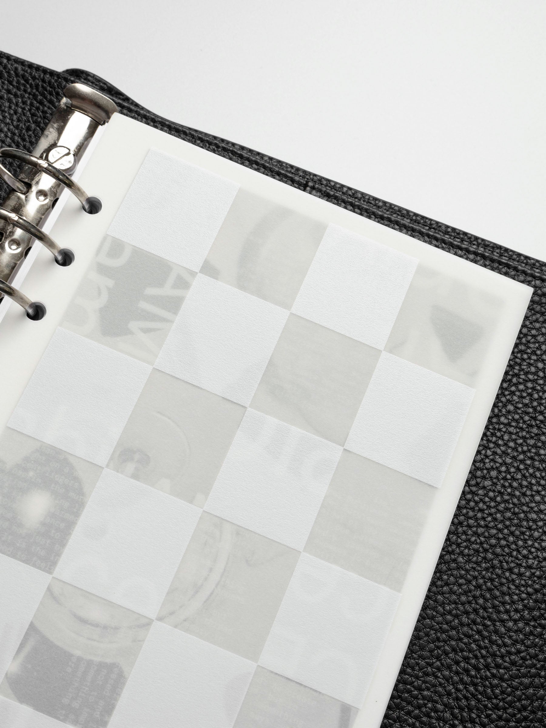 A close-up of the Ambiance Planner Dashboard checkered layer in an A5 planner, highlighting the frosted translucent material and white square pattern.