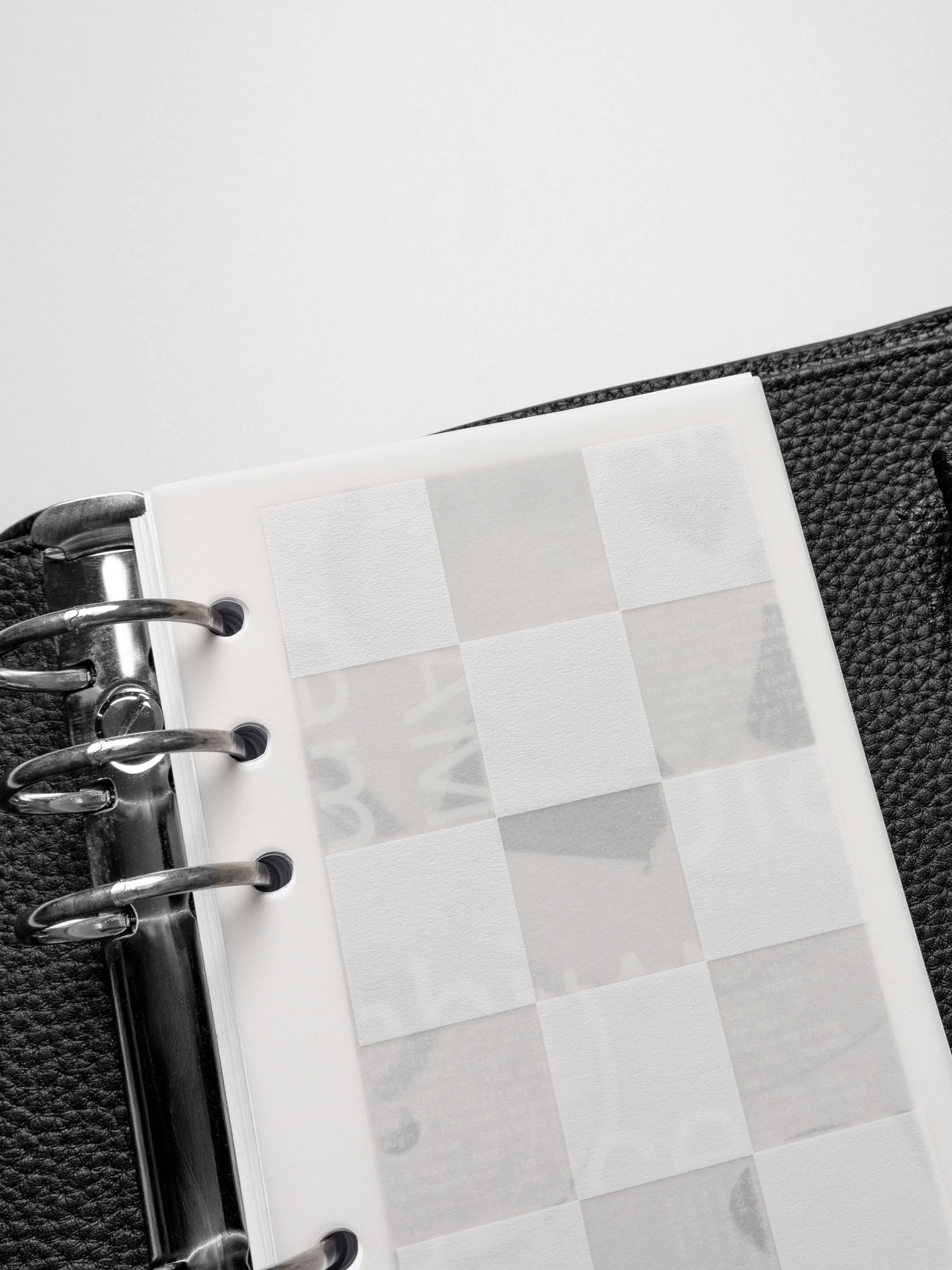 Close-up of the Ambiance Dashboard Trio's translucent grid layer within a black leather planner, emphasizing the textured square details.