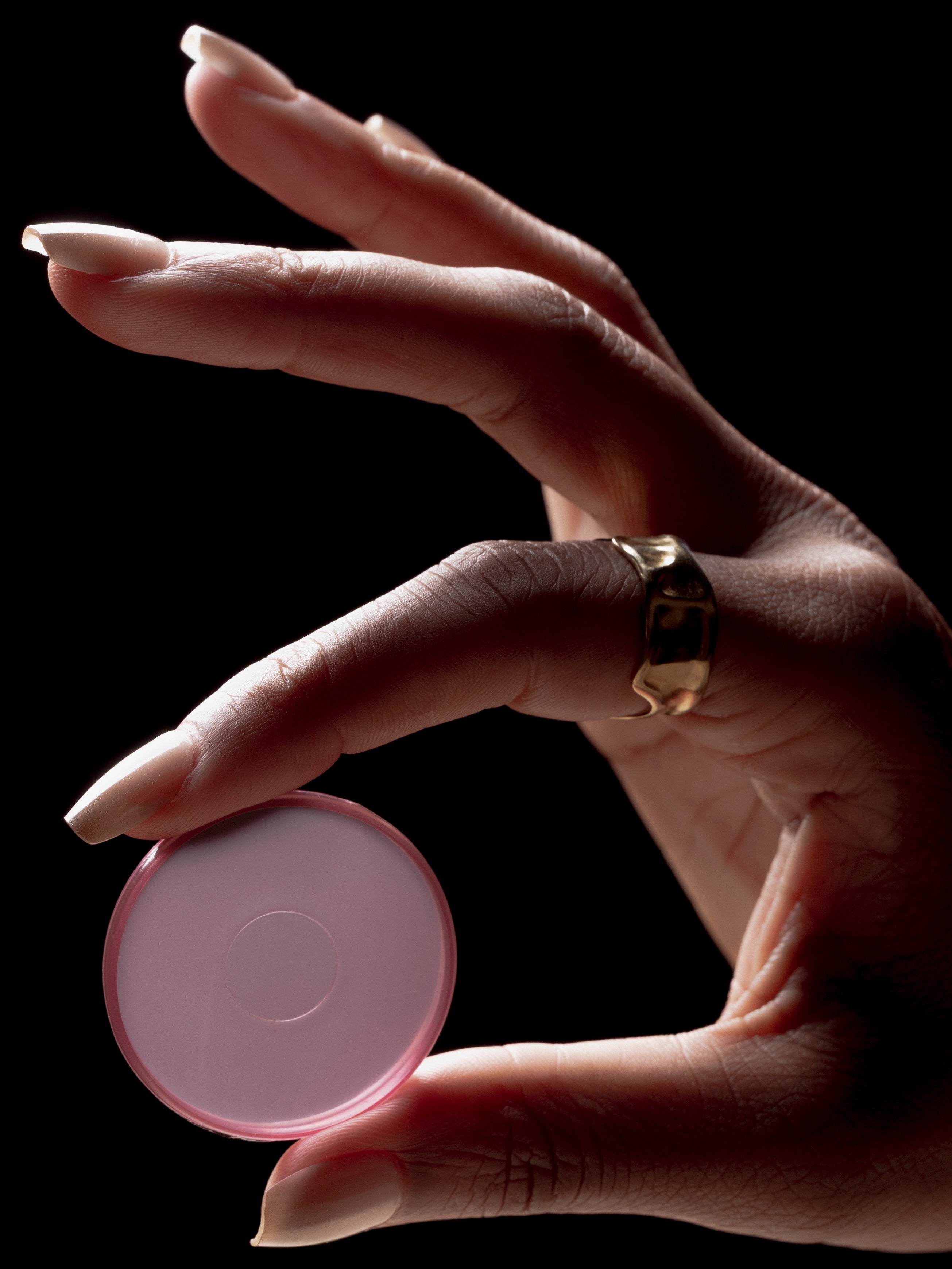 Hand holding one Transparent Planner Disc in the color Bordeaux against a dark background.