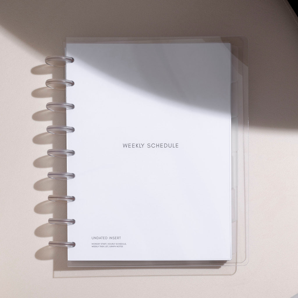 HP Classic-sized Beginner Planner Bundle, protected by a clear vinyl cover, designed for your weekly schedule, placed on a white table with gentle shadows.