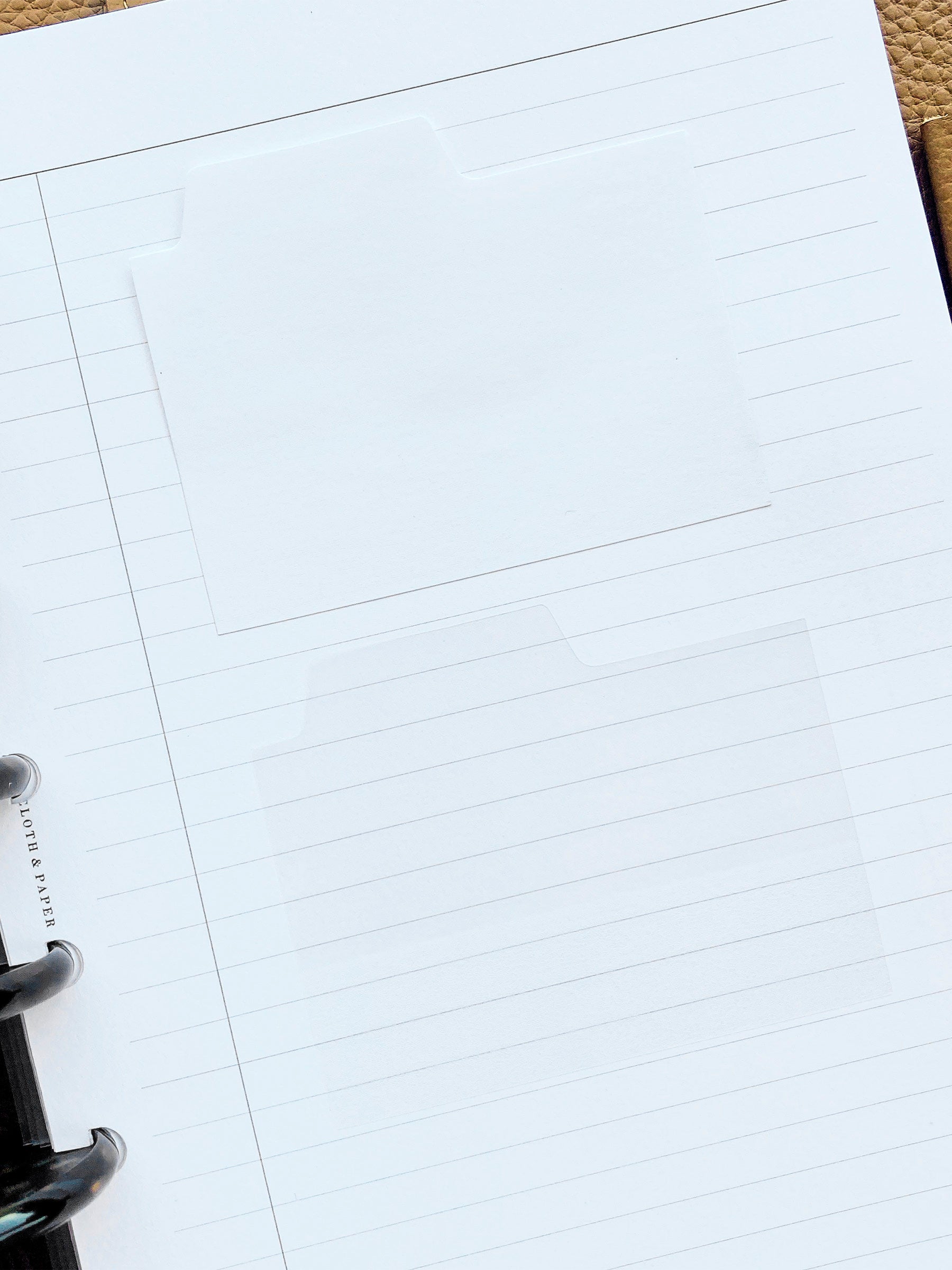 Blank Tab Sticky Note Set, Blanc, Cloth and Paper. One matte and one transparent sticky note from the set placed on a task insert. The transparent sticky note is layered over the bottom right corner of the matte sticky note.