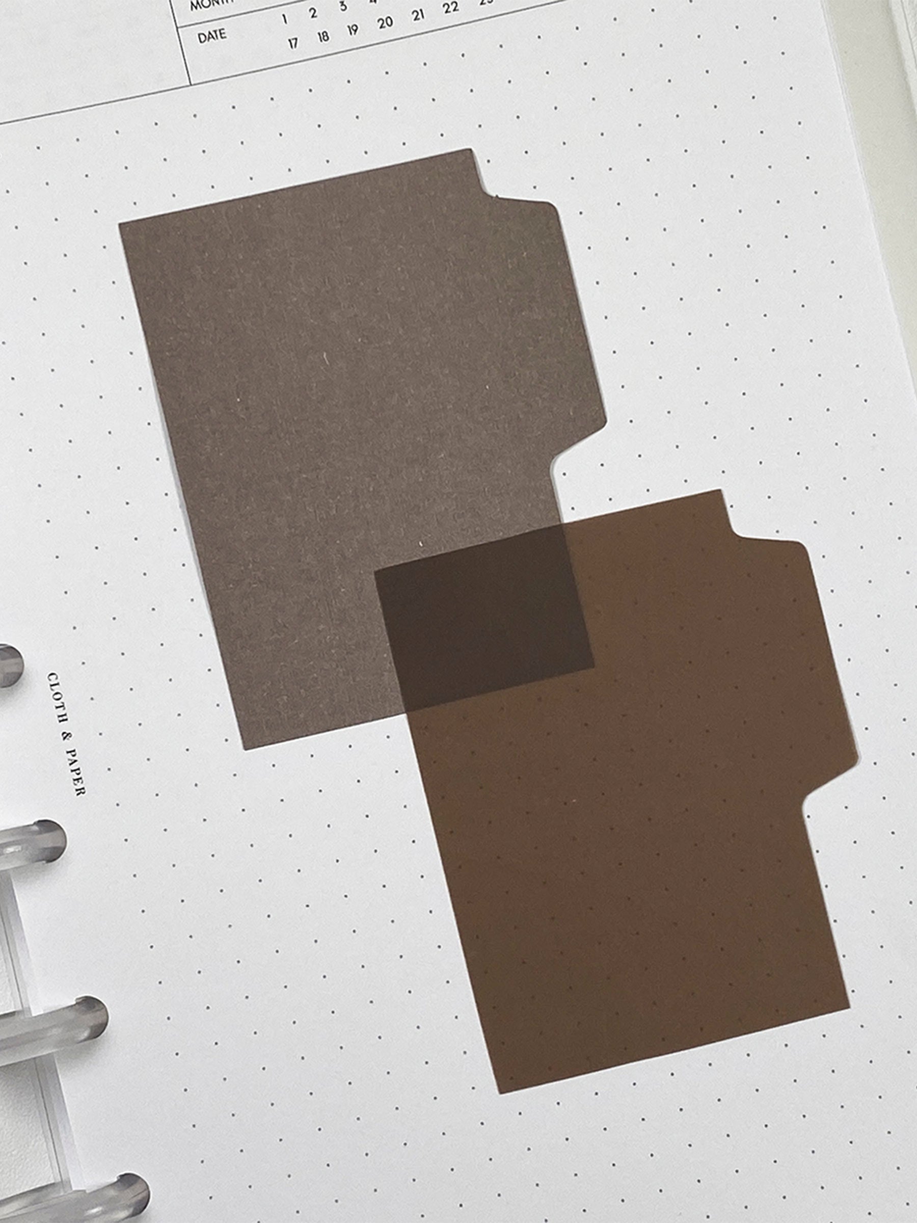 Blank Tab Sticky Note Set, Espresso, Cloth and Paper. One matte and one transparent sticky note from the set placed on a task insert. The transparent sticky note is layered over the bottom right corner of the matte sticky note.