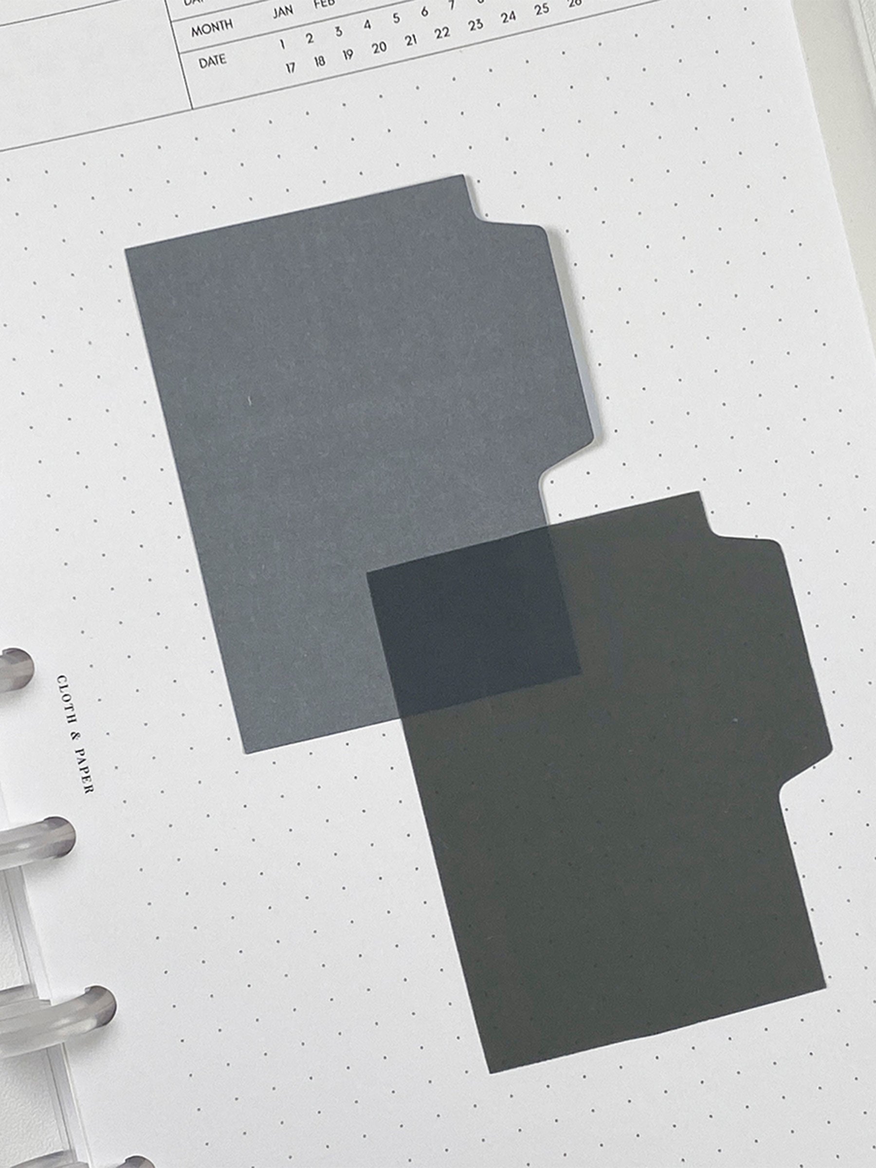 Blank Tab Sticky Note Set, Stone, Cloth and Paper. One matte and one transparent sticky note from the set placed on a task insert. The transparent sticky note is layered over the bottom right corner of the matte sticky note.