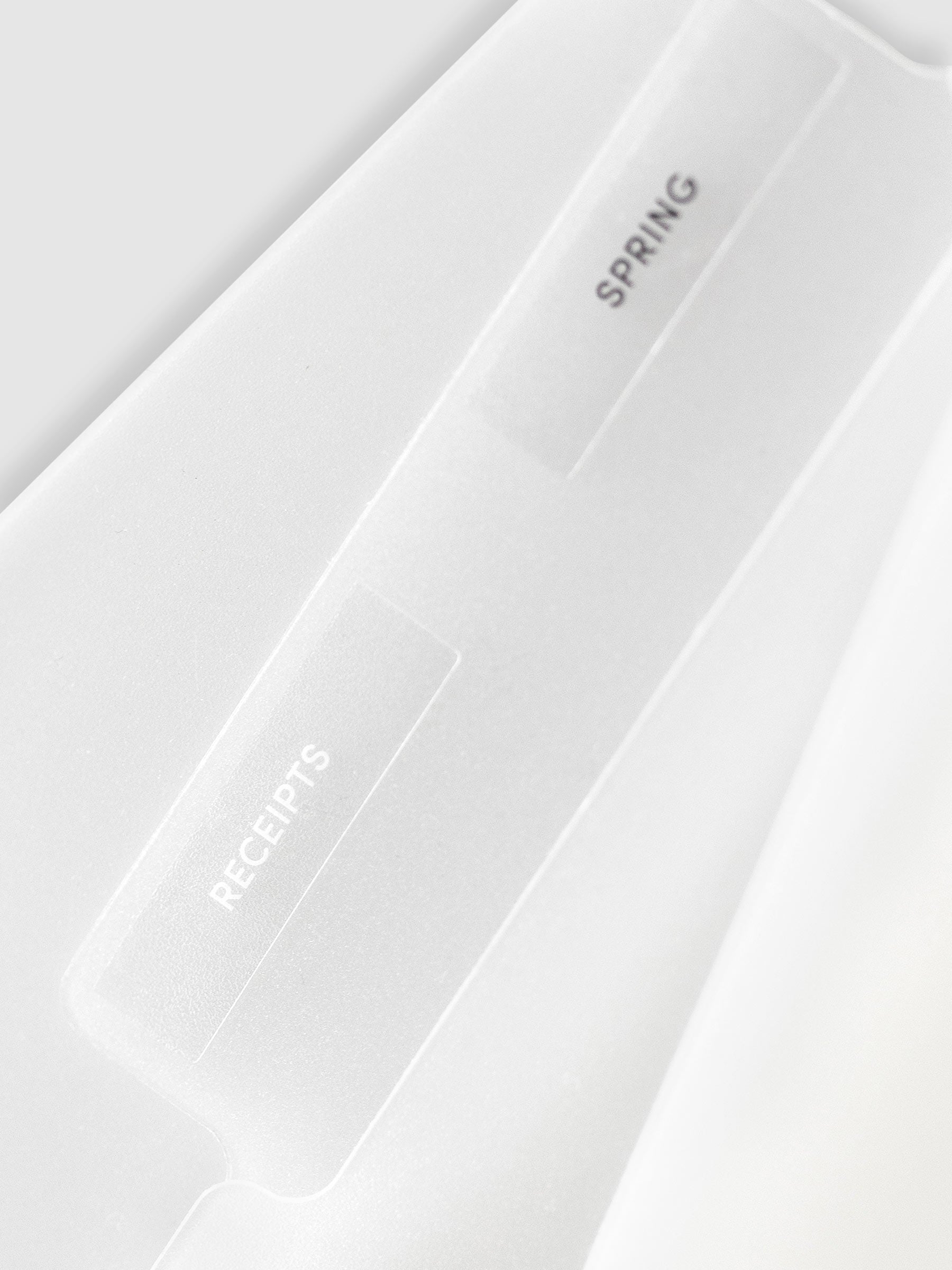 Two folders layered over each other with labels attached. One label reads "Spring" in black text and the other reads "Receipts" in white text.