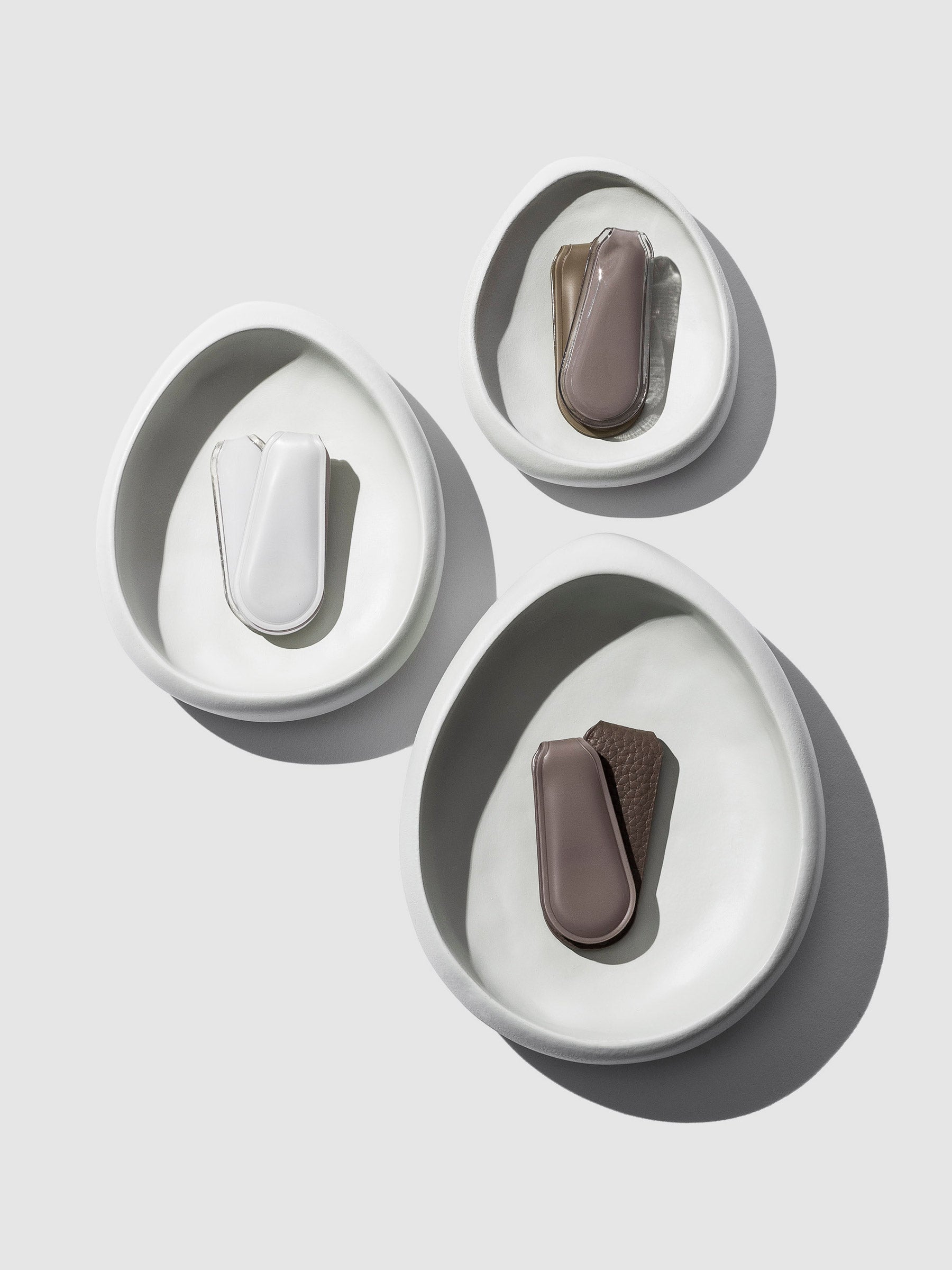 Nested set of 3 Catch-All Trays, artfully arranged with 2 Cloth and Paper clips neatly placed inside each tray, creating a harmonious blend of organization and elegance. Against a clean neutral background, shadows add depth and dimension to this stylish ensemble