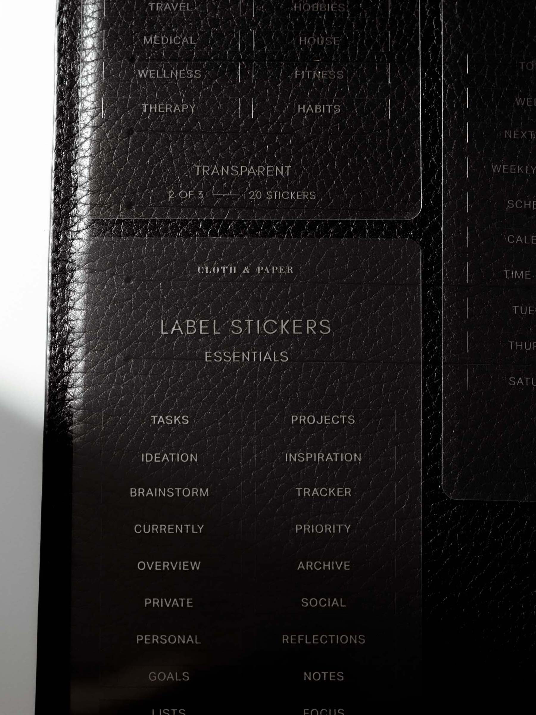 Close up image of the Clear Label Stickers against a black leather planner