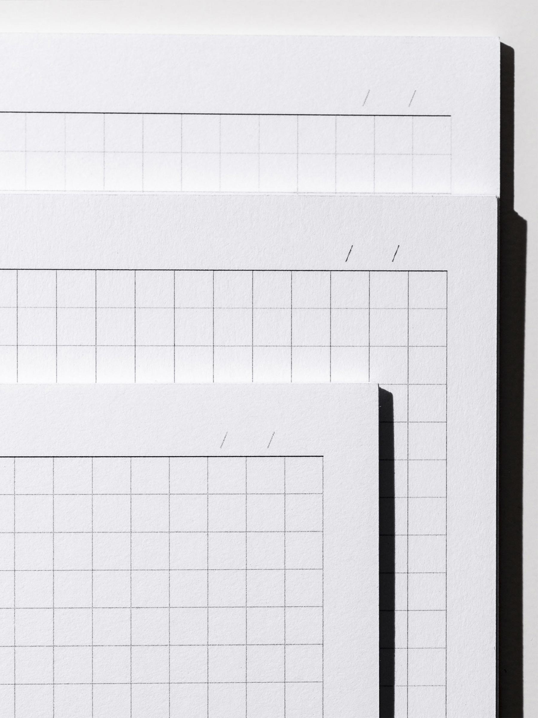 Closeup of three inserts, which are layered over top of each other from smallest to largest. Each is showcasing their lined column and graph note page format. The undated calendar header is also visible on all three inserts.