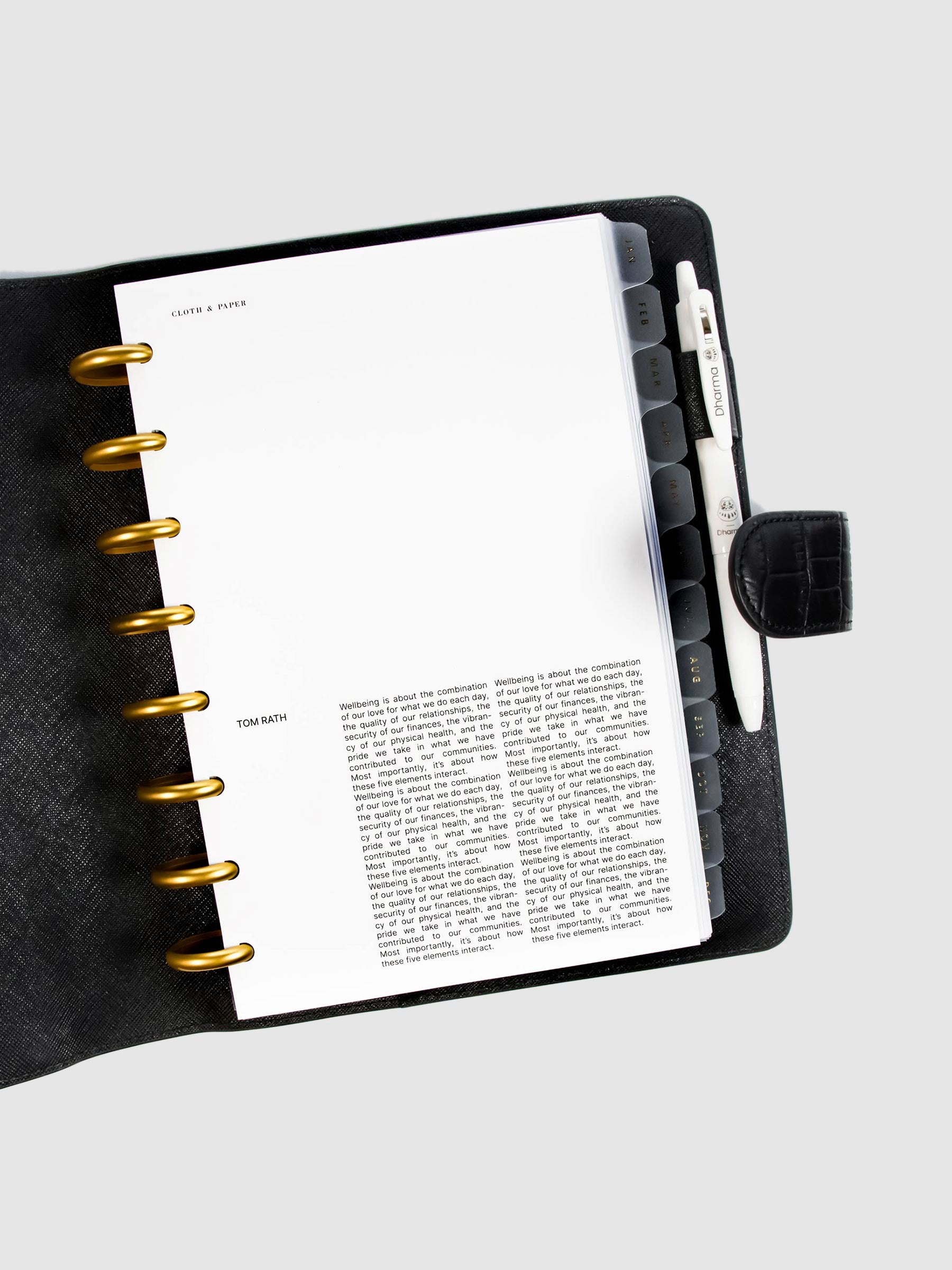 Crosshatch Planner Dashboard styled inside a discbound notebook in a black leather agenda cover. The discbound planner has gold rings, and there is a white pen in the leather cover's pen loop.