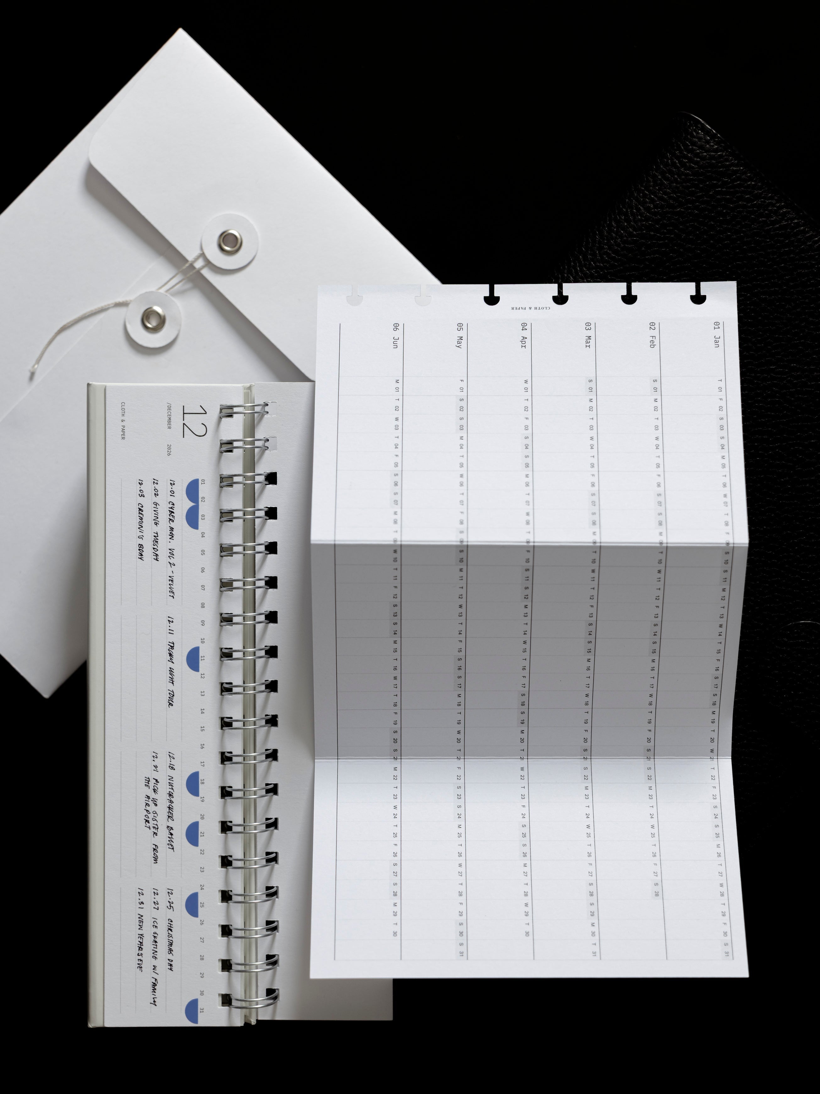 Envelope, desk calendar, and a fold out yearly planner insert on a dark background.