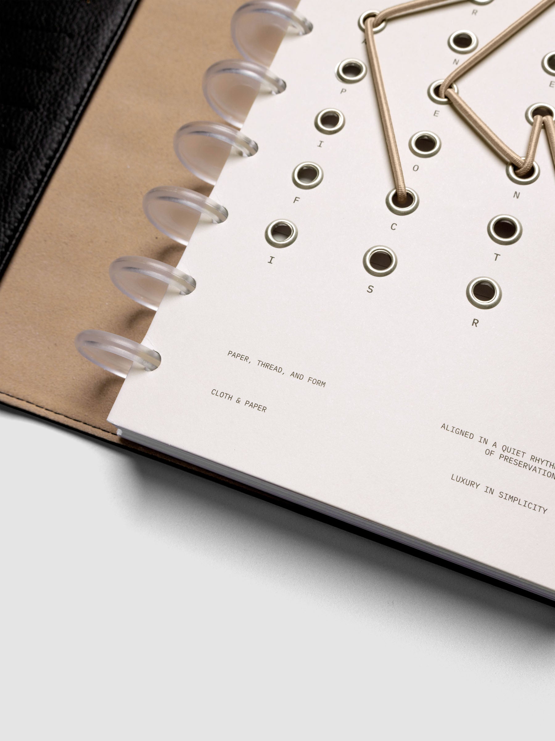Cadence Dashboard with grommets and string on beige cardstock shown close up in a discbound planner.