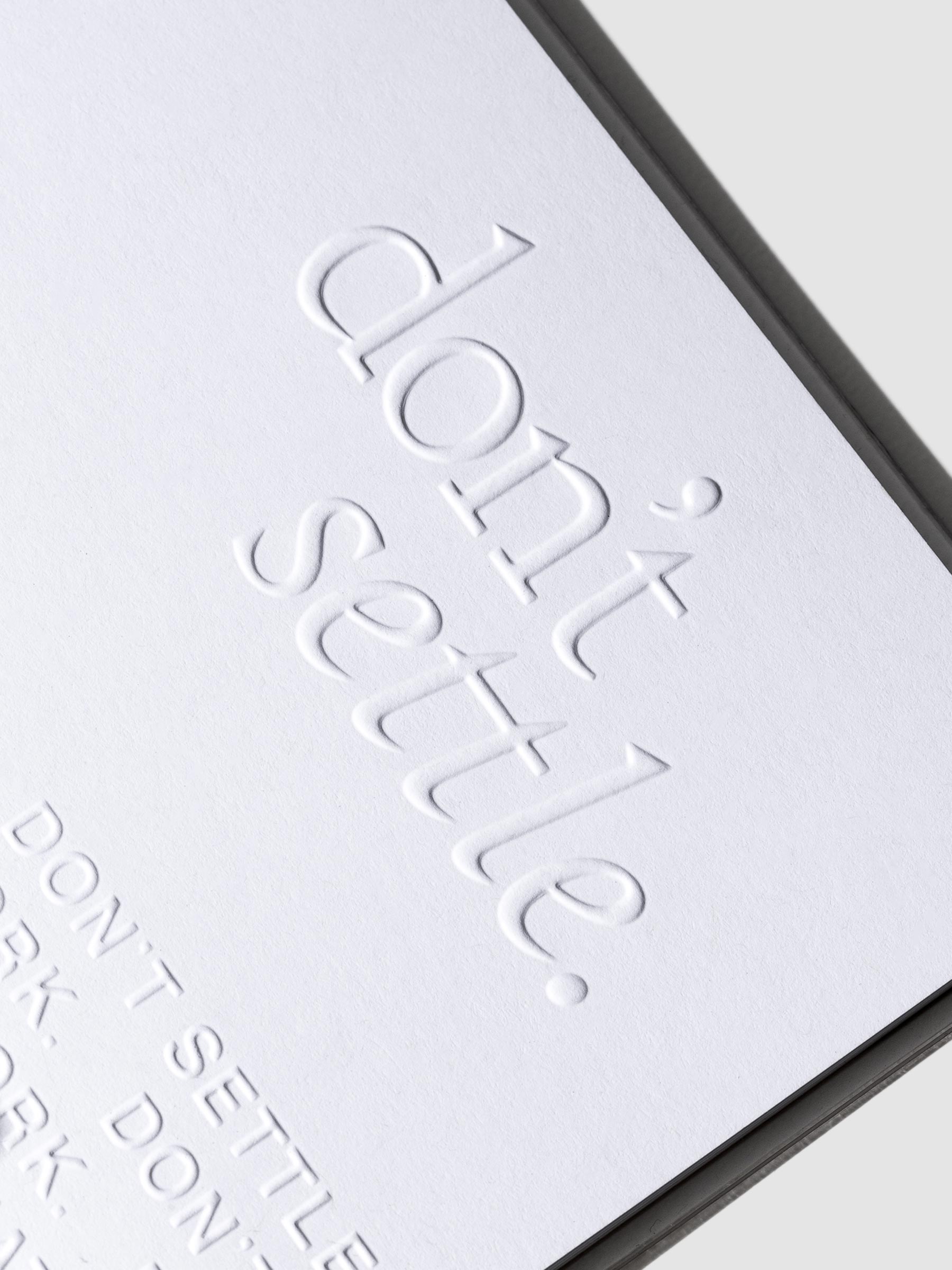 Closeup of embossed text that reads "don't settle."