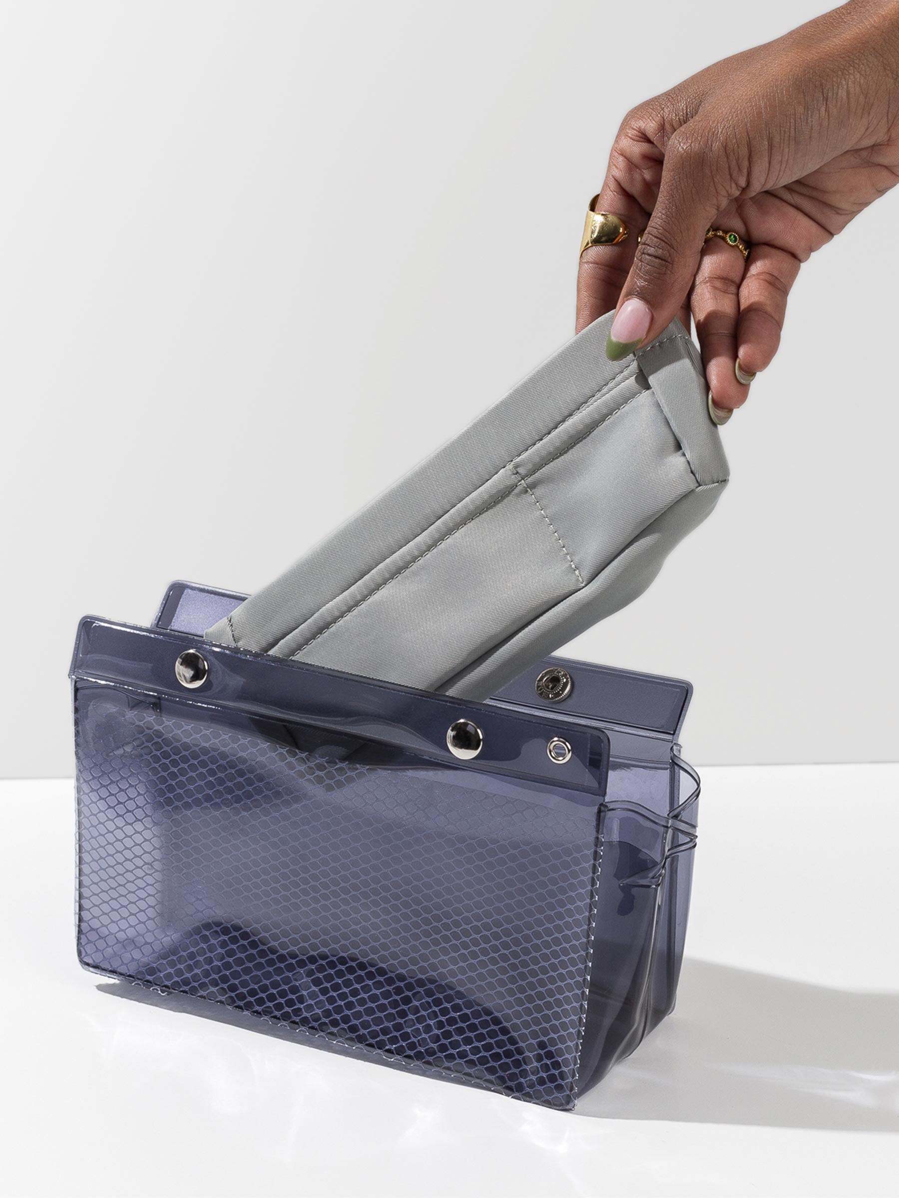 Double Carryall Pouch and Ristretto Liner, Cloth and Paper. Pouch displayed on a neutral background. A hand is shown lifting a Ristretto liner out of the Carryall Pouch.