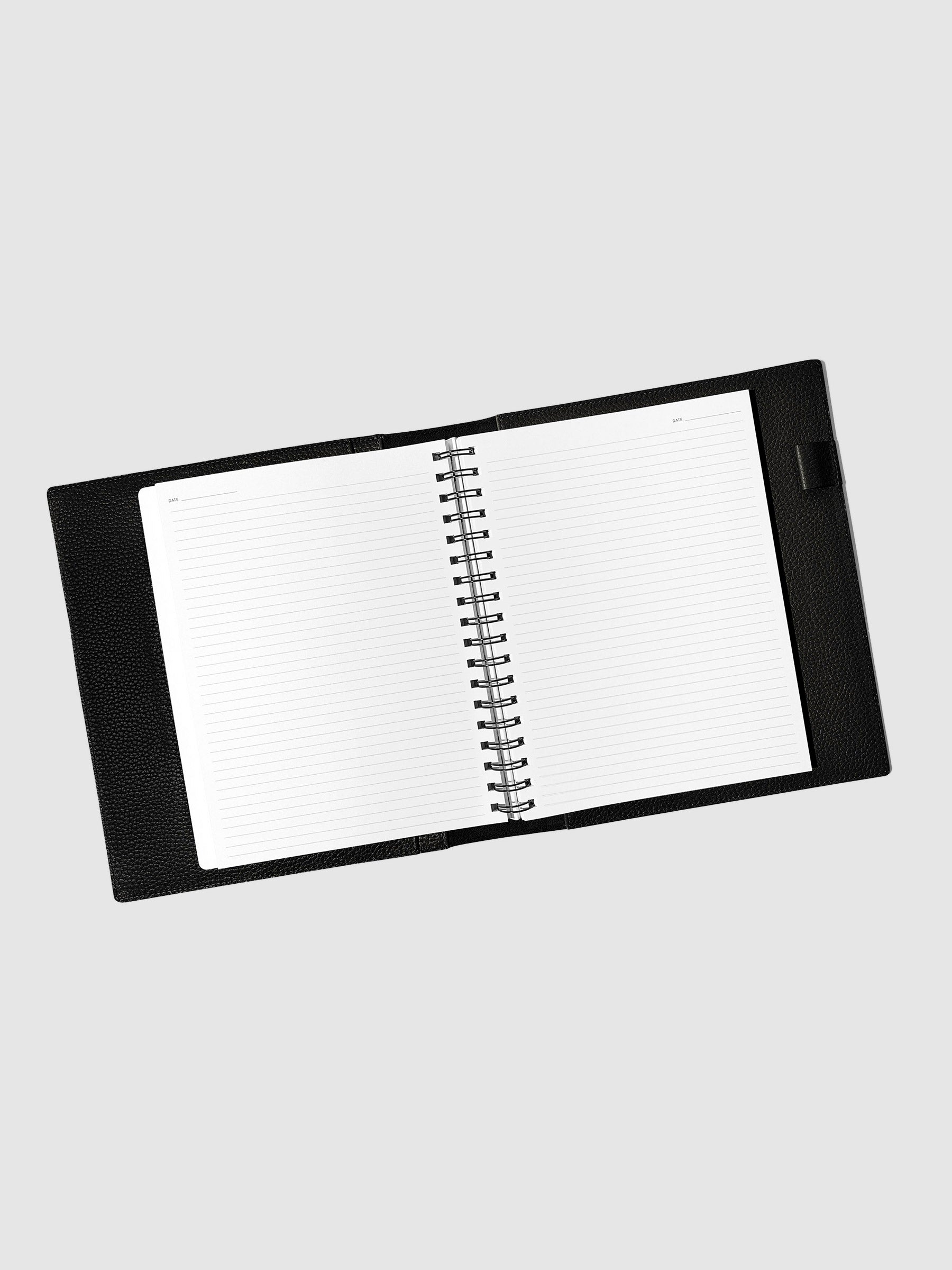 Notebook spread open inside a black leather agenda. Design shown is graph.