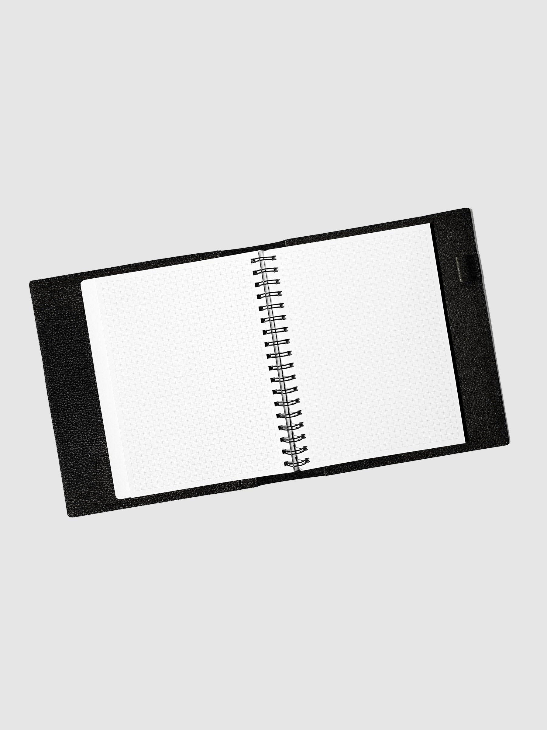 Notebook spread open inside a black leather agenda. Design shown is graph.