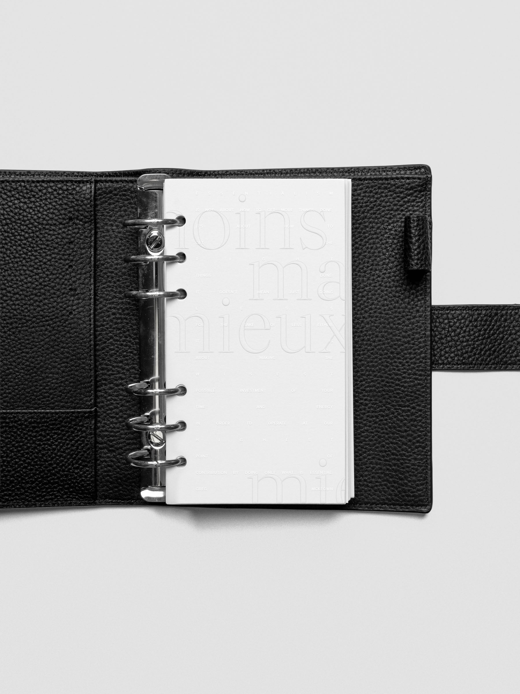 Essentialism Dashboard Duo reading "moins mai mieux" in size Personal; shown ringbound in a leather agenda.