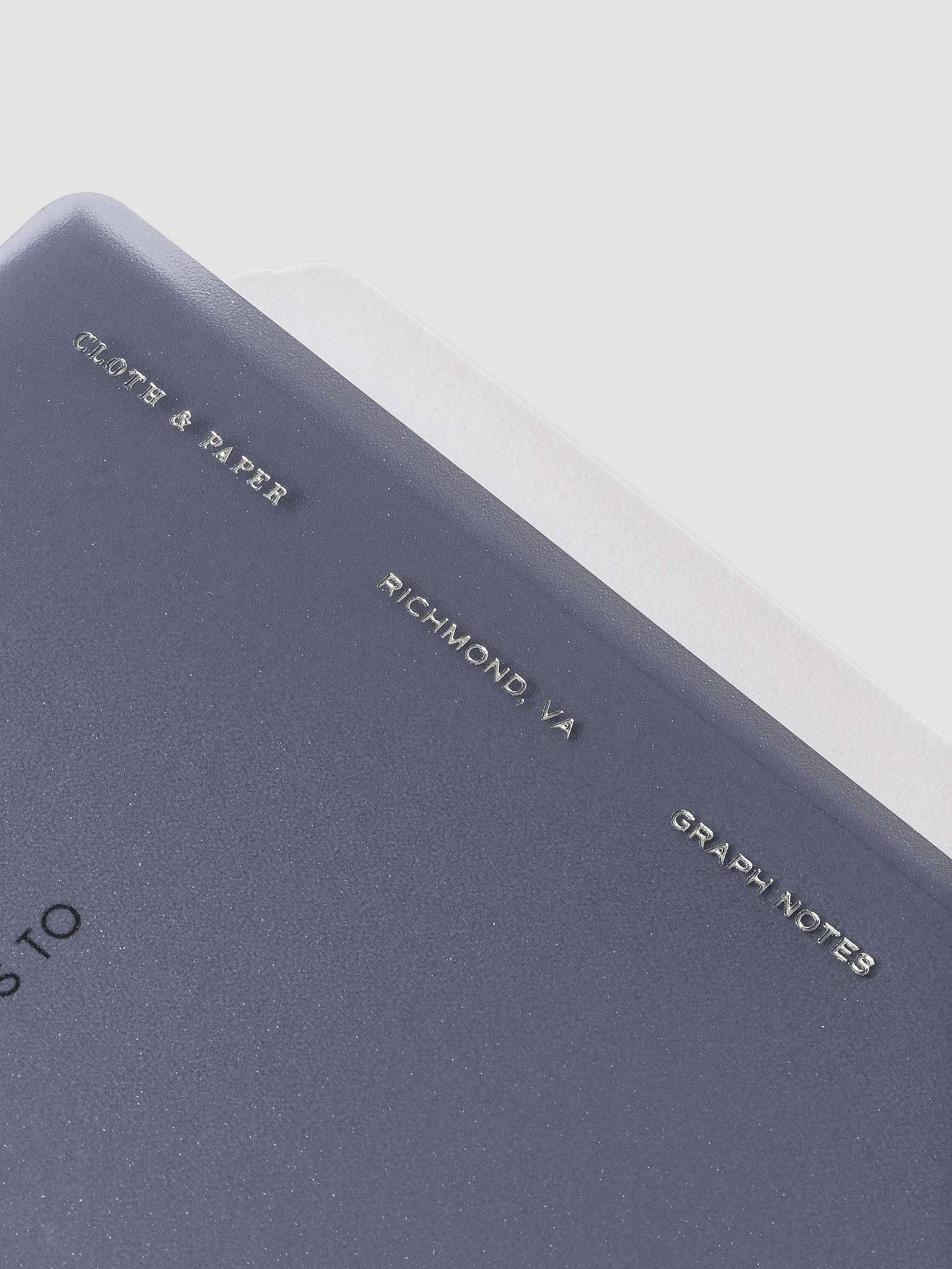 Closeup of tinted plastic notebook. Embossed text reads "Cloth & Paper | Richmond, VA | Graph Notes"