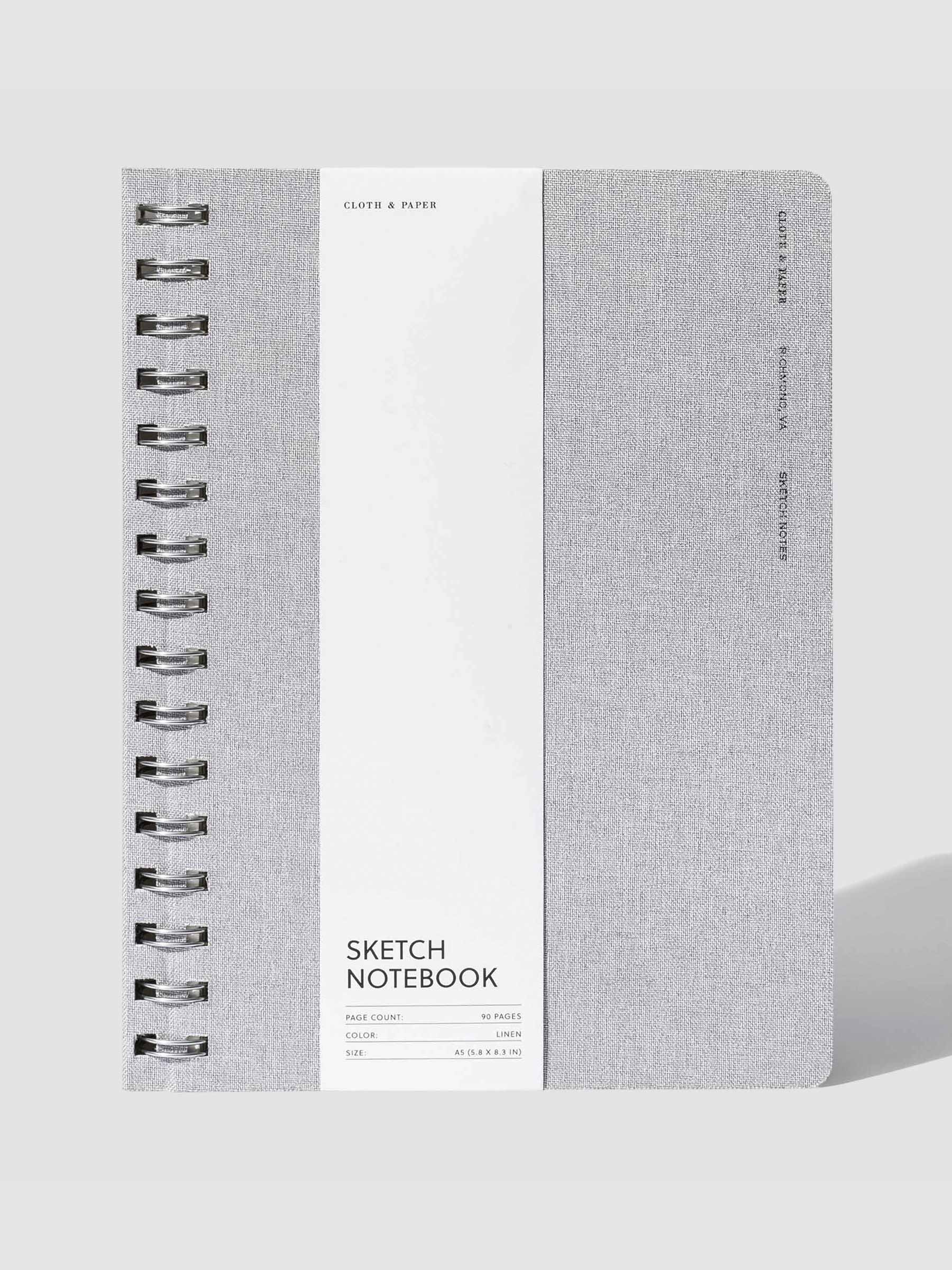 Linen notebook displayed with its packaging on a neutral background.