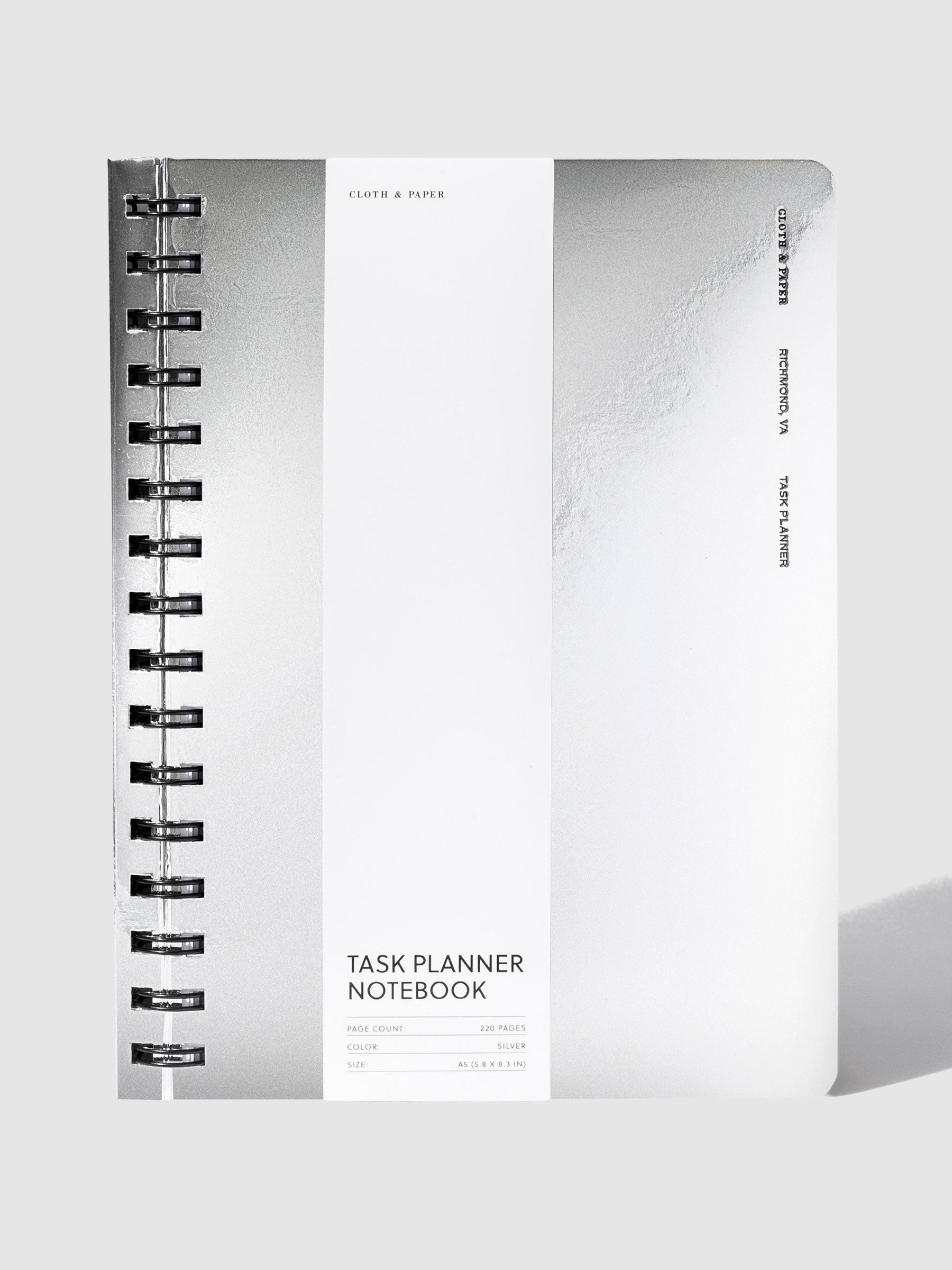 Exotic Spiral Notebook, A5, Silver, Cloth and Paper. Silver notebook displayed with its packaging on a neutral background.