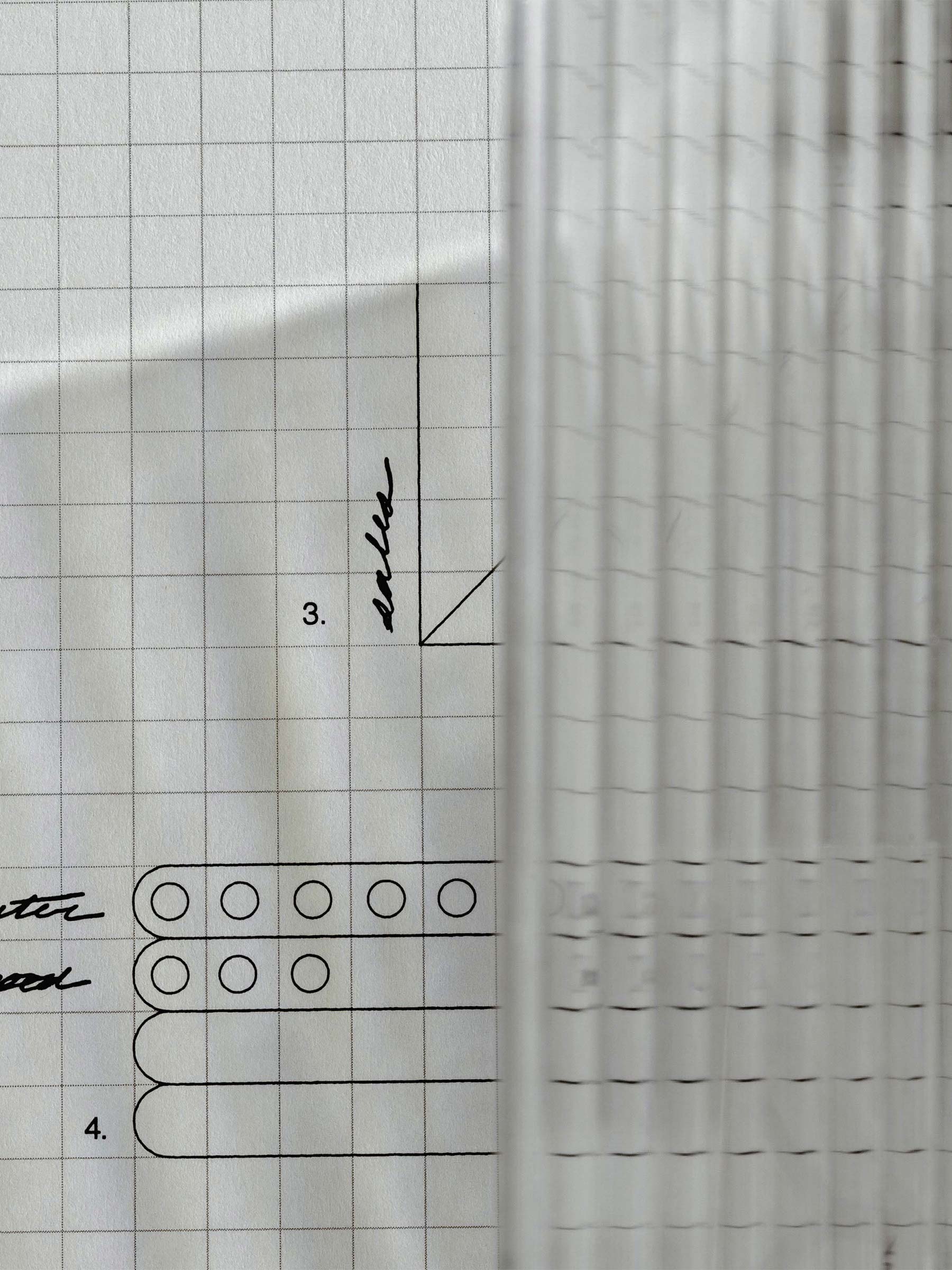 Photo focusing on the texture and light reflections caused by the dashboard on a piece of graph paper.