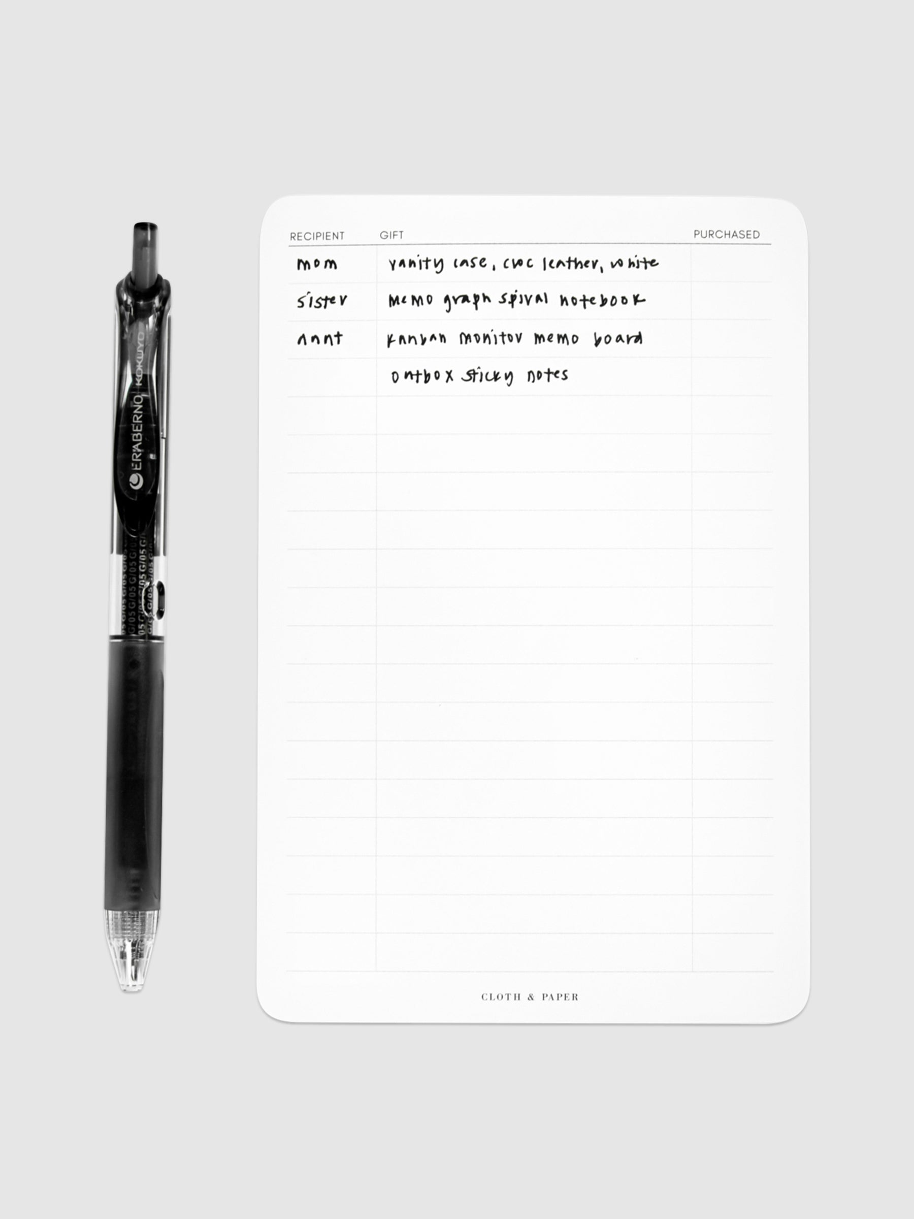Gift List Notepad, Cloth and Paper. Notepad styled with writing on it and pen perpendicular to it, against a neutral background.