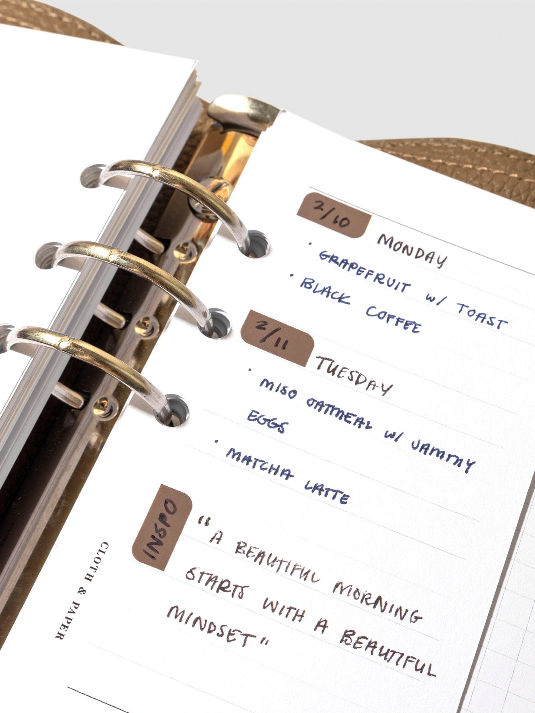 Insert in use inside a leather planner. It has sample text filled out and several stickers decorate different sections of the insert.