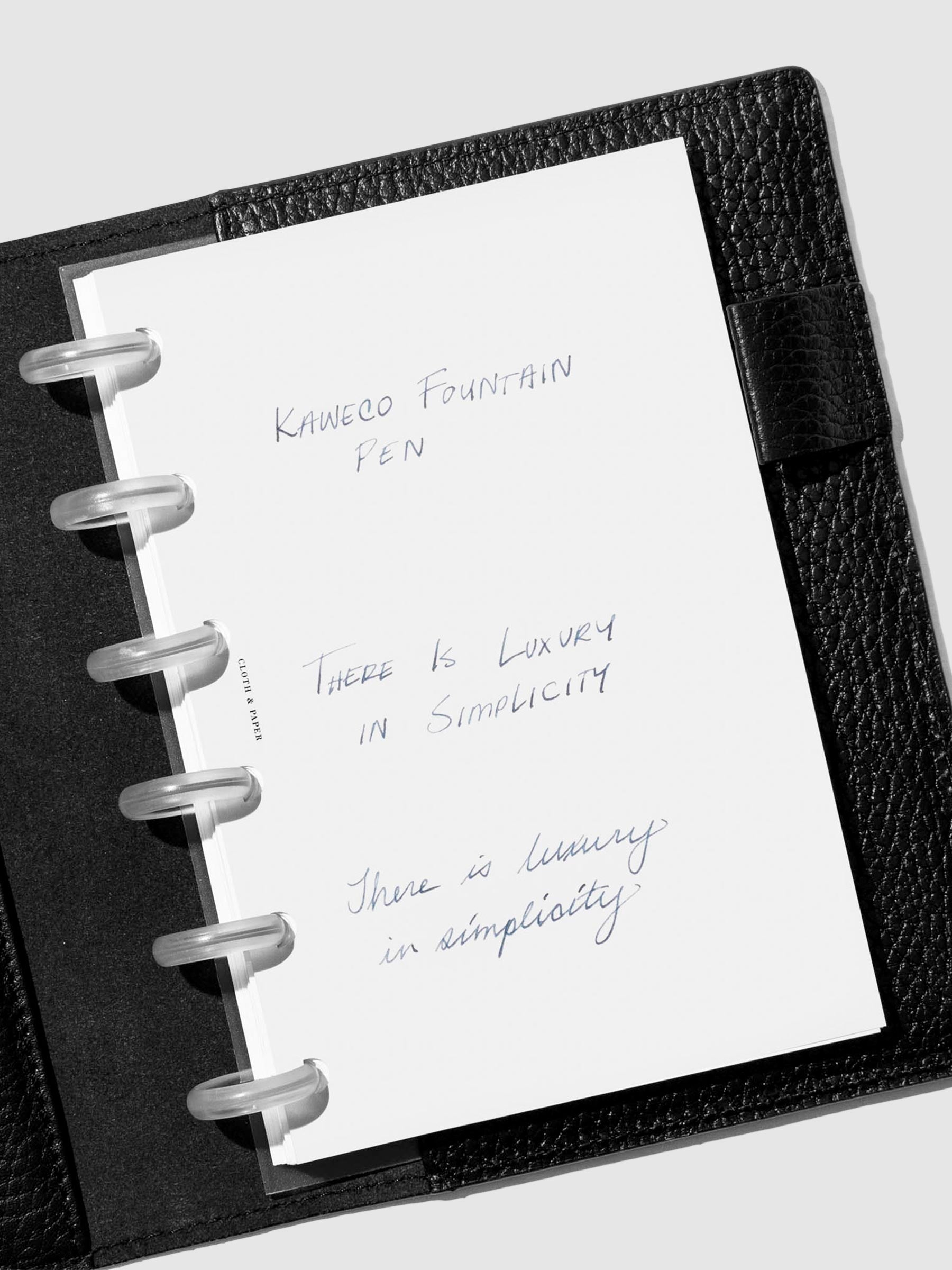 Fine nib writing sample shown in a black leather folio.