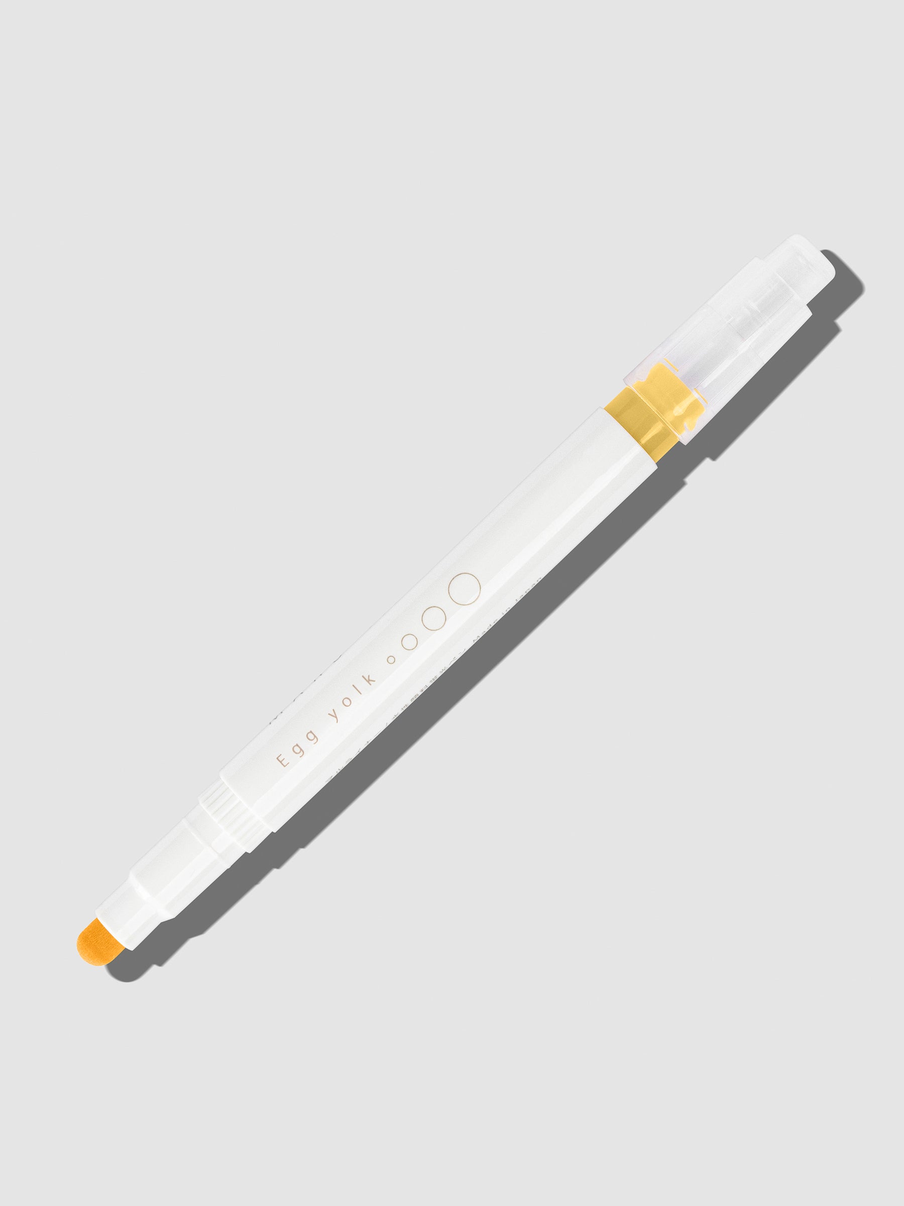 Egg Yolk highlighter with tip exposed and cap posted to the end of its barrel on a neutral background.