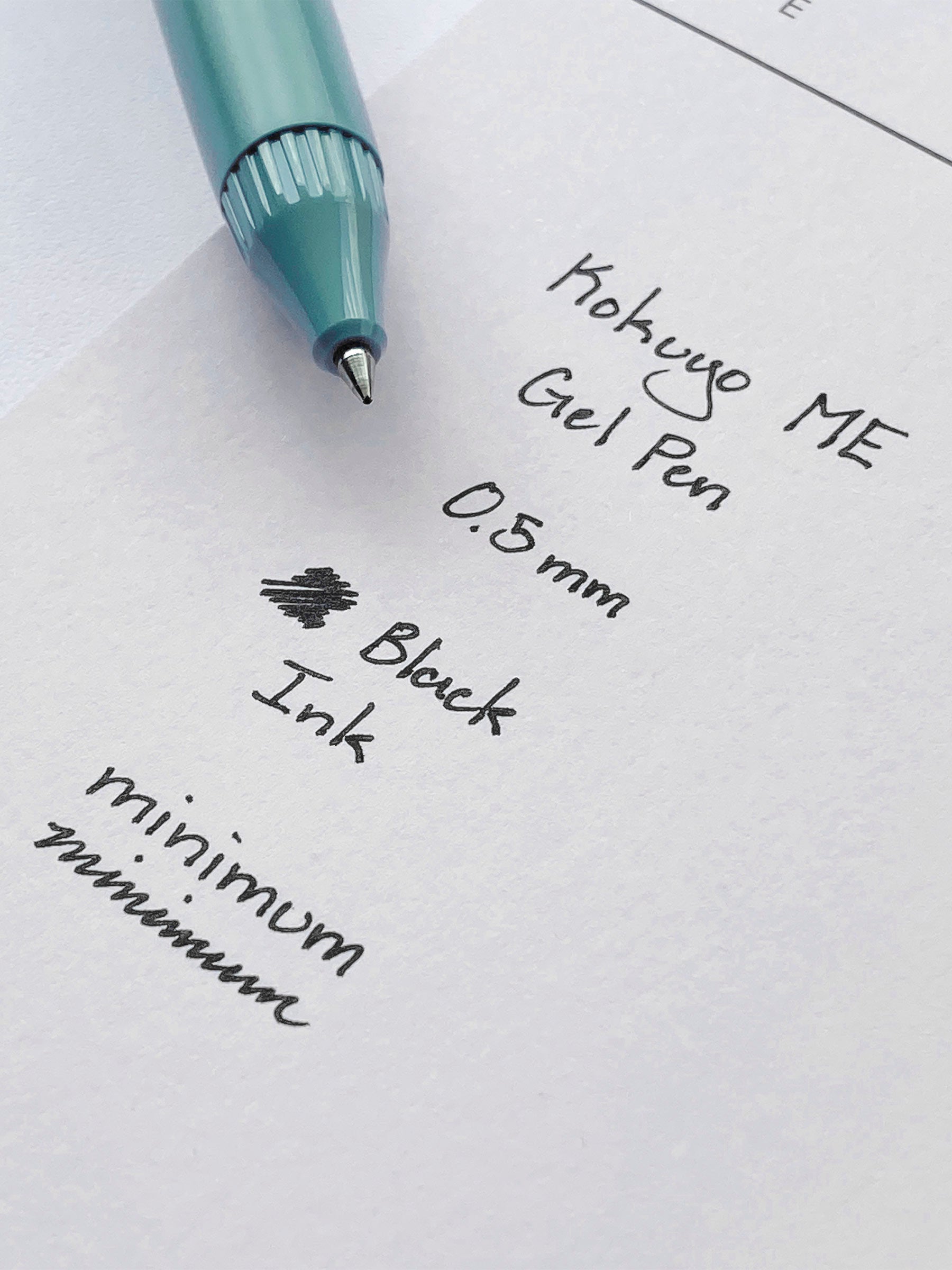 Kokuyo ME Gel Pen, Smoky Sky, Cloth and Paper. Pen resting on pen test sheet displaying writing sample.