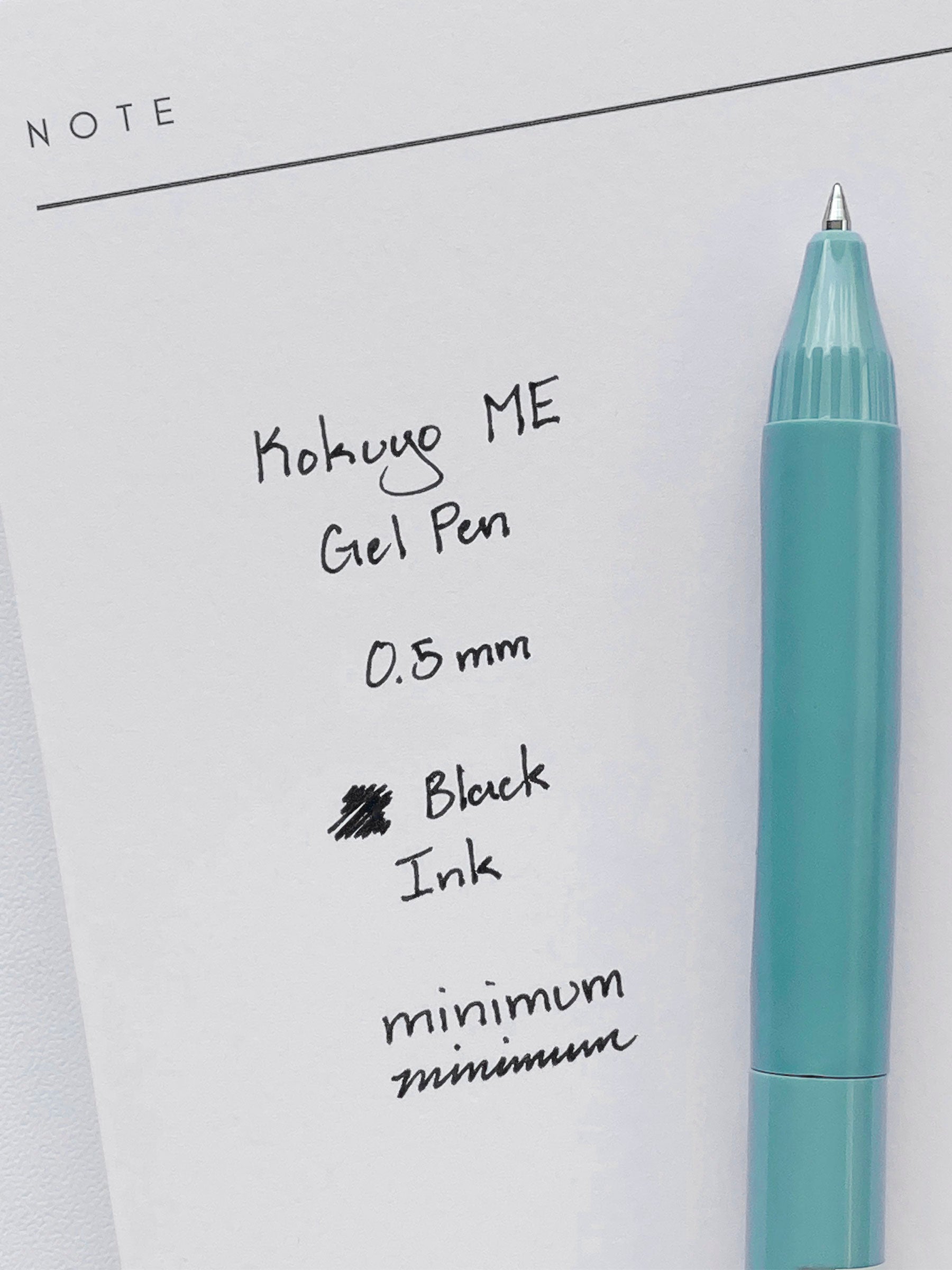 Kokuyo ME Gel Pen, Smoky Sky, Cloth and Paper. Pen resting on pen test sheet displaying writing sample.