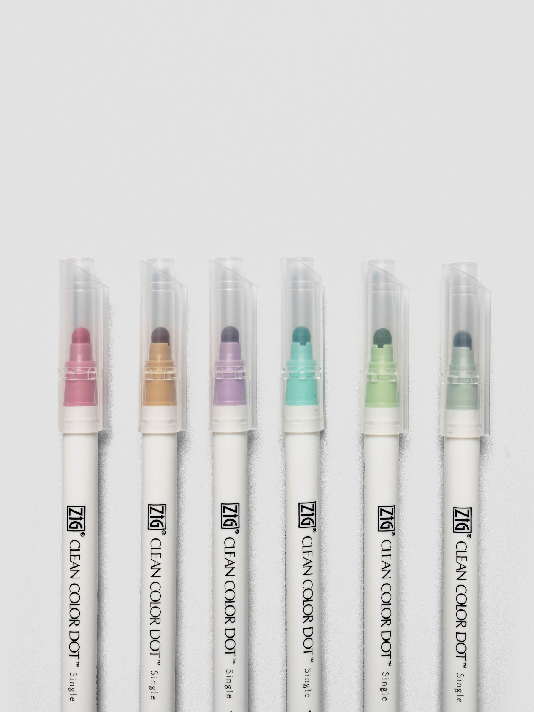 Close-up view of the six Kuretake ZIG Clean Color Dot Markers standing upright with clear caps and visible dot tips.