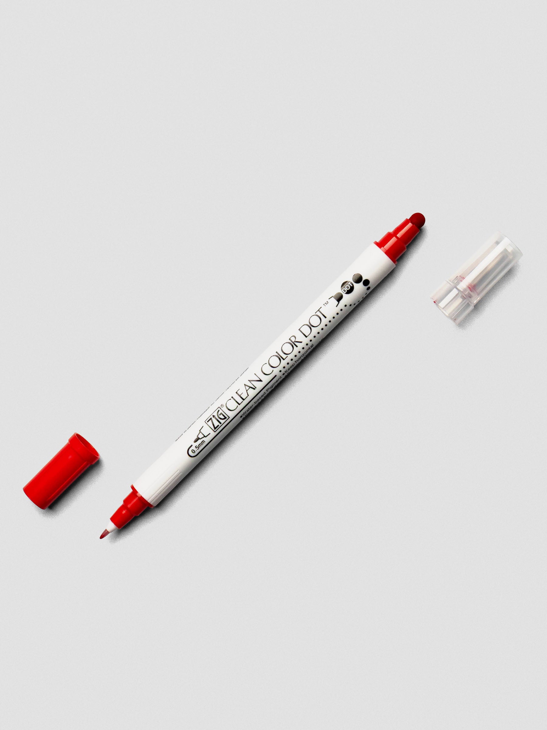 Red Kuretake ZIG Clean Color Dot Dual Tip Marker with caps off, displaying both the fine tip and dot tip on a light background.