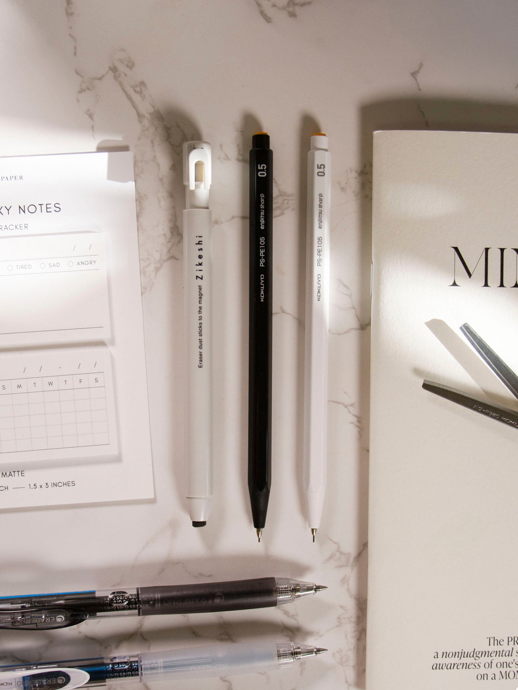 Kutsuwa Zikeshi Eraser, Gray, Cloth and Paper. Eraser styled with pencils, pens, sticky notes, notebook, and scissors, all on a marble surface.