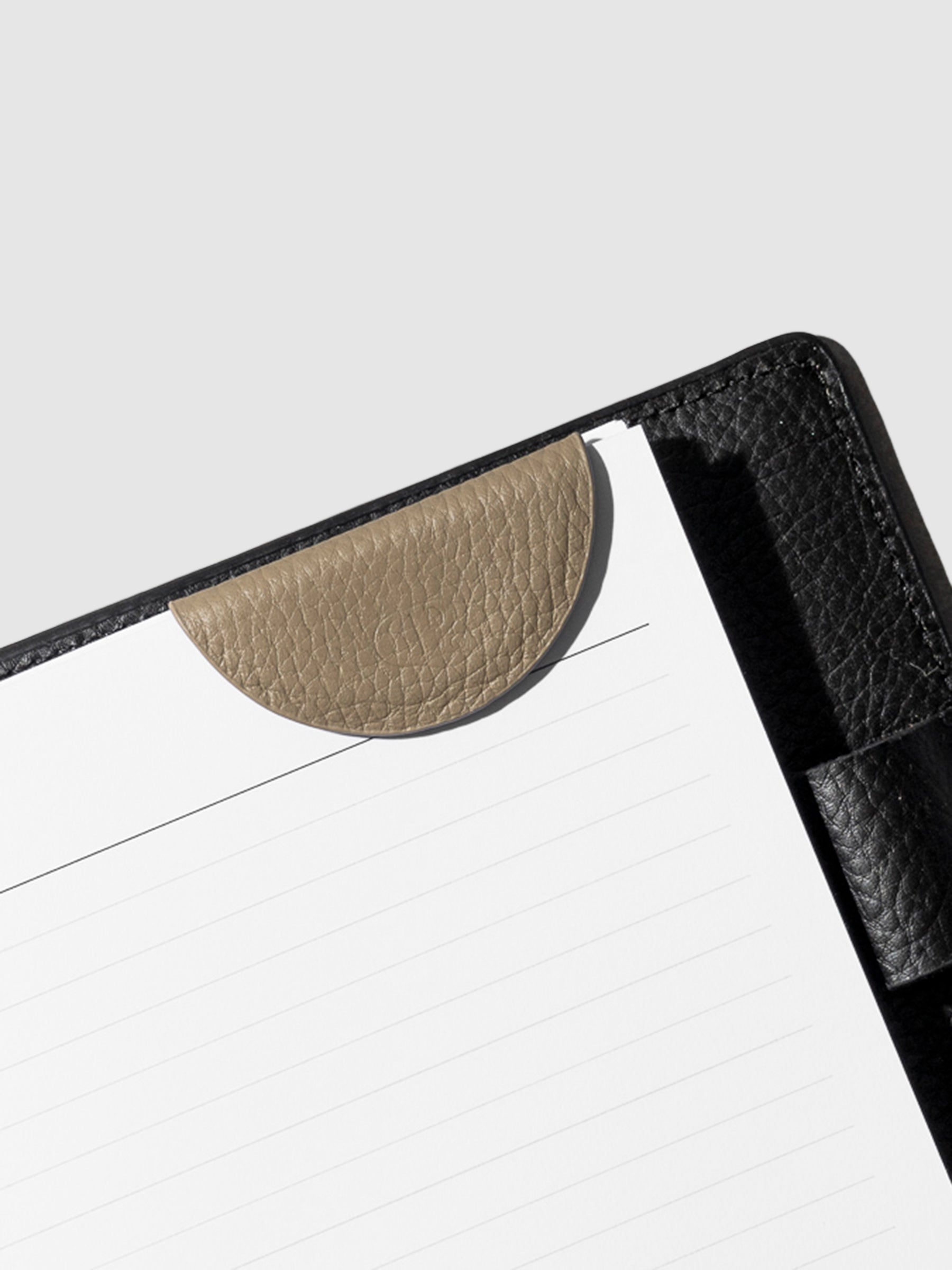 Brown bookmark in use inside a black leather agenda.