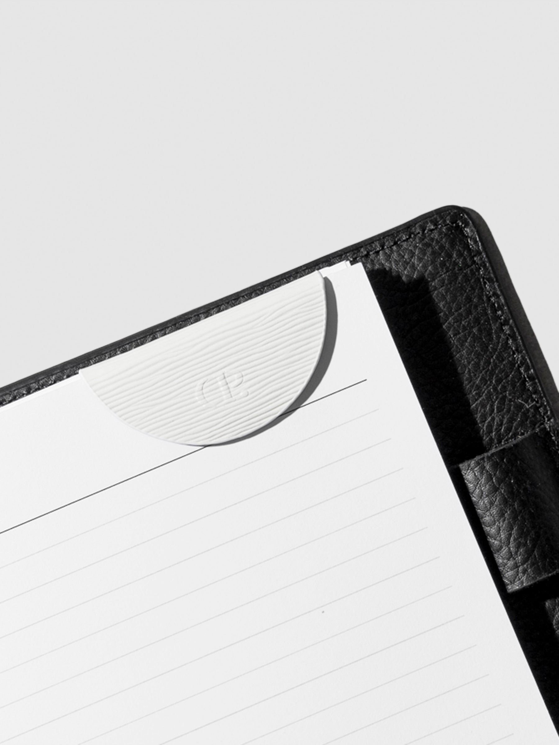 White bookmark in use inside a black leather agenda.