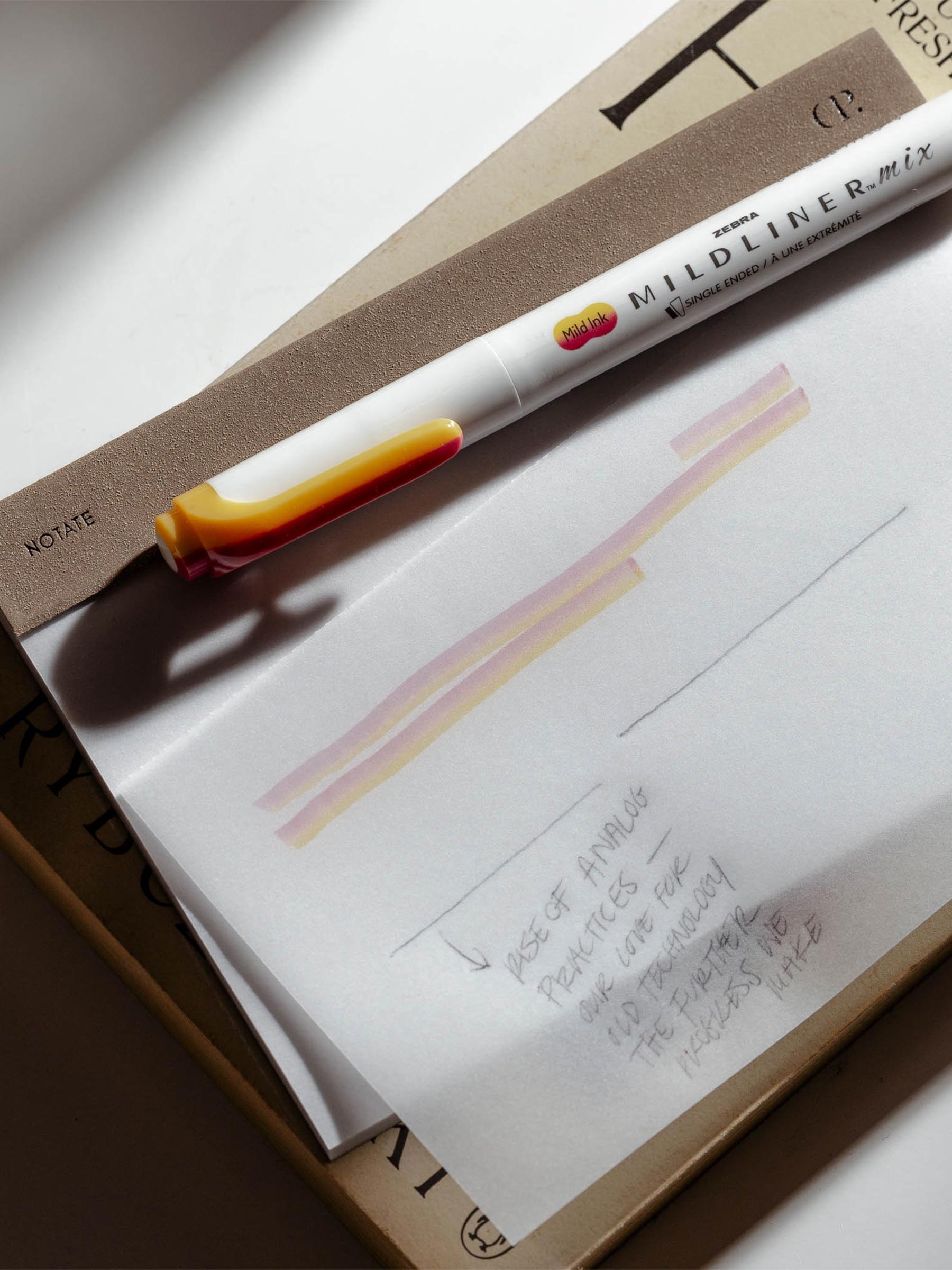 Notepad in use on a neutral background. One of the pages has been written on in pencil and highlighter.