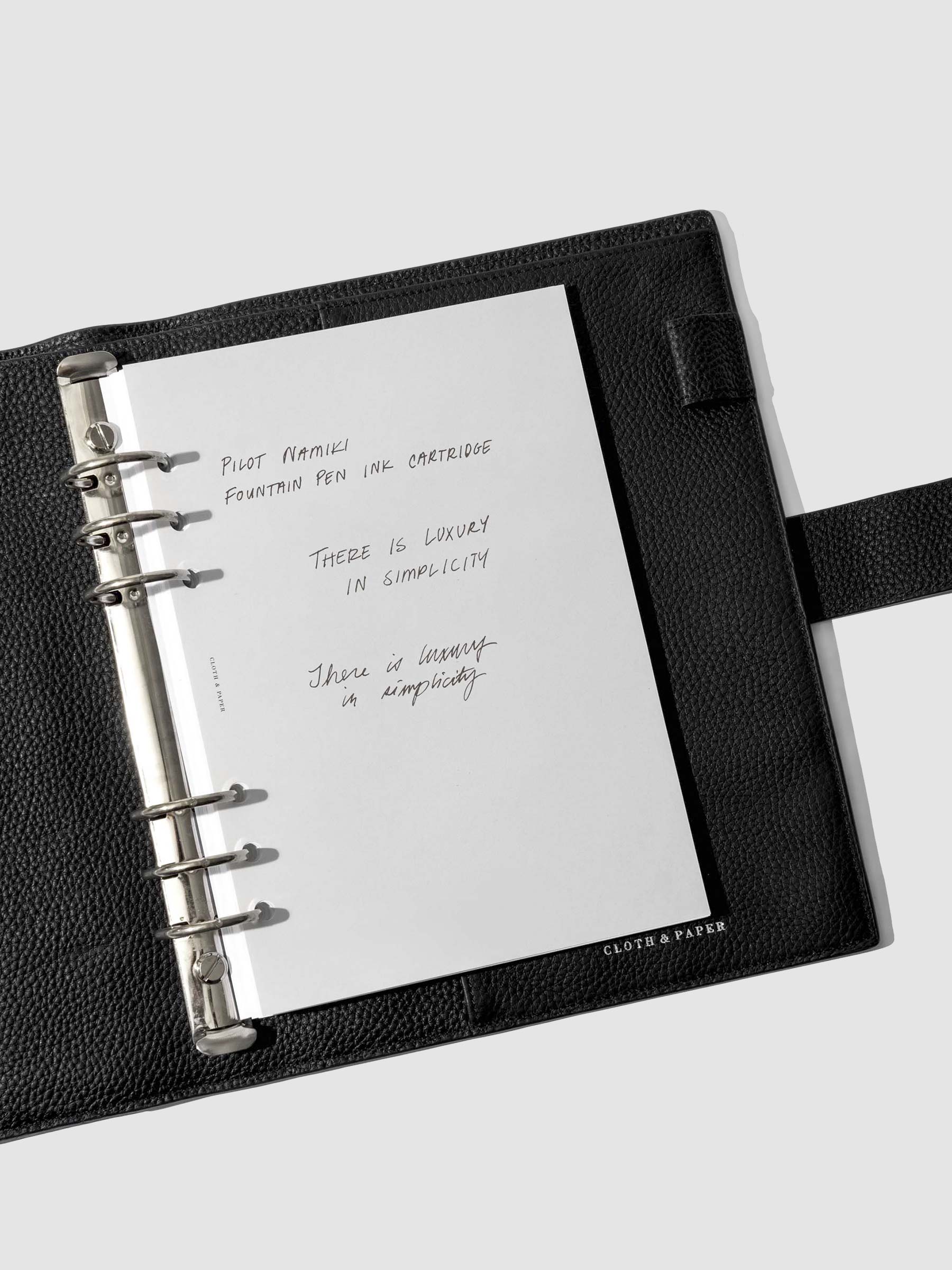 Writing sample shown in a black leather folio.