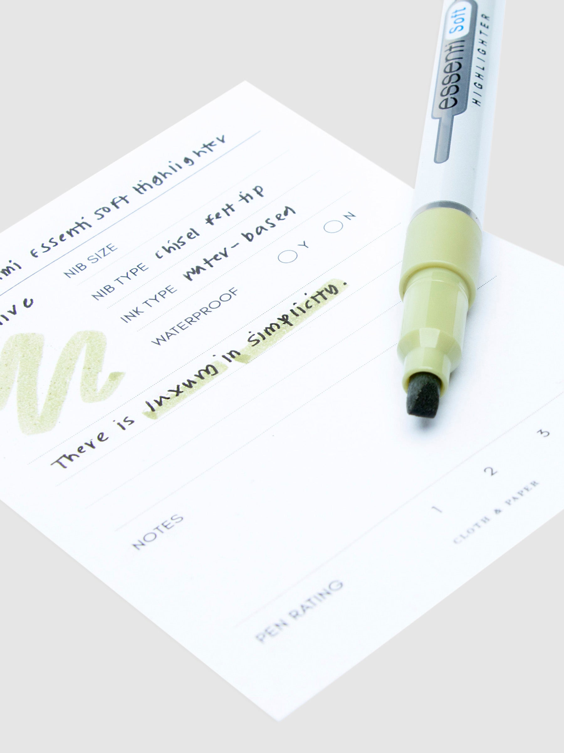 Close up on the felt nib of the Pastel Olive highlighter resting on a pen test sheet displaying a writing sample.