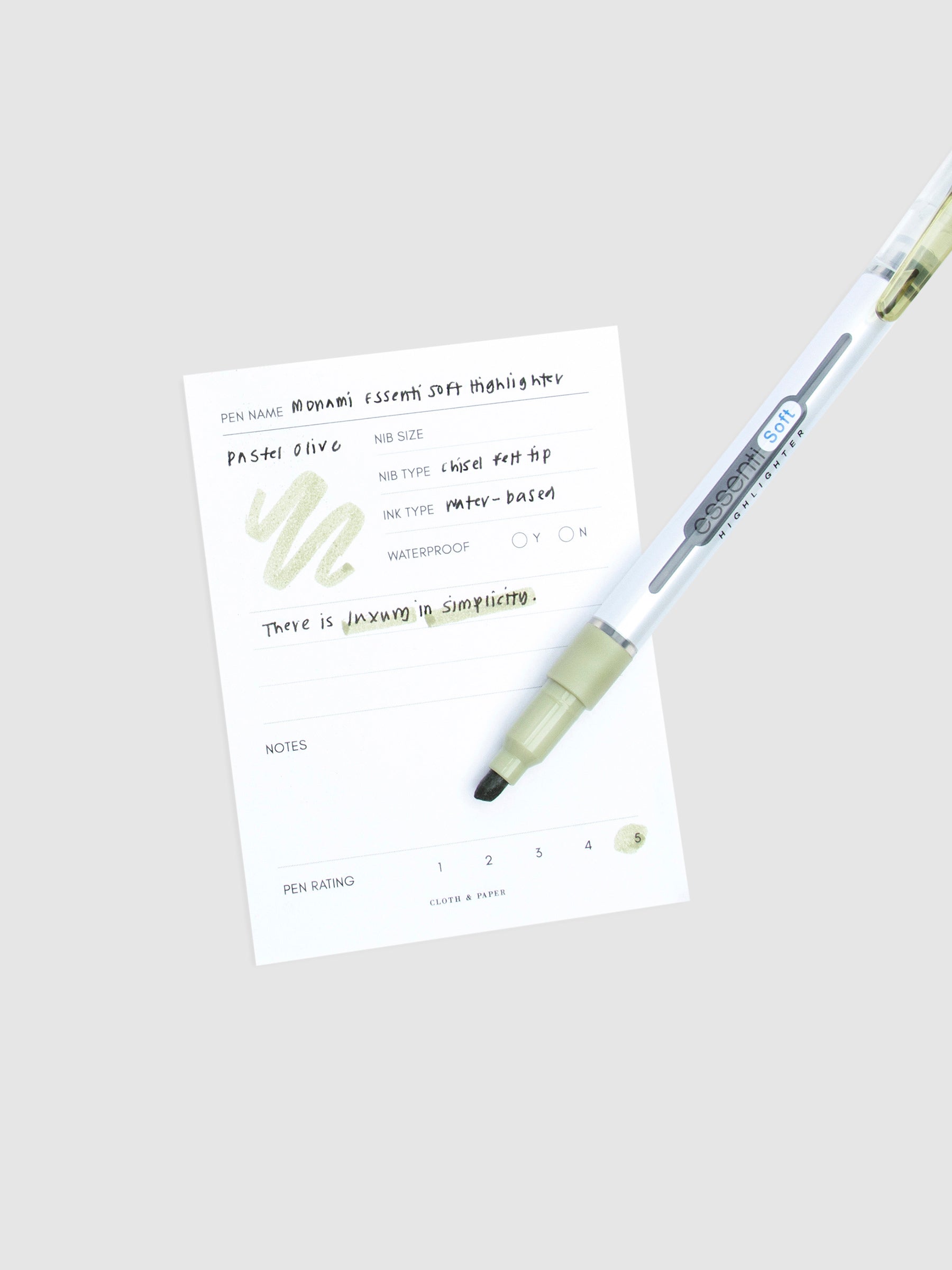 Pastel Olive highlighter resting on a pen test sheet displaying a writing sample detailing the highlighter's specs.