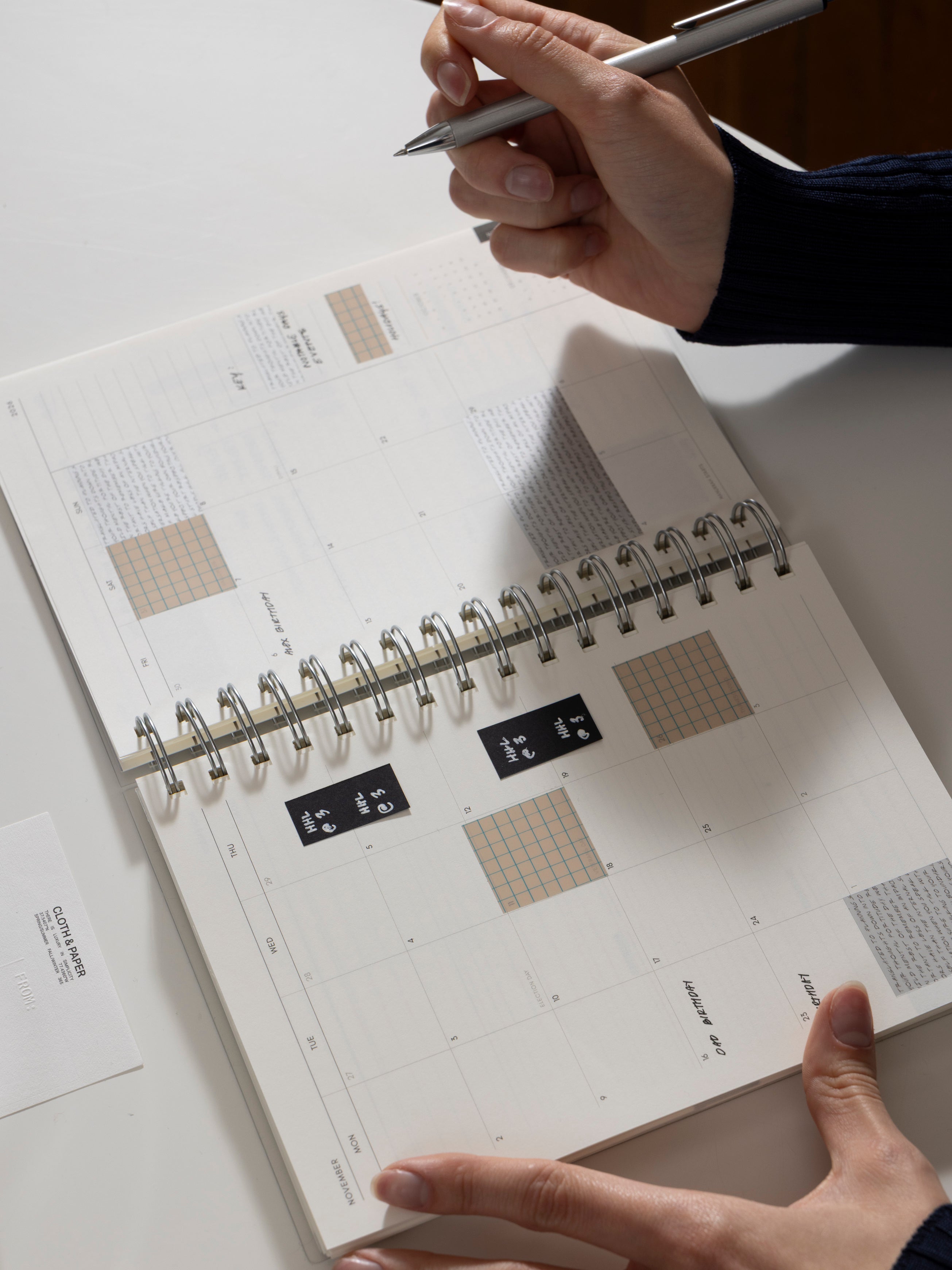 Open spiral notebook with Square Page Flags Vol. 1 in use on a monthly spread.