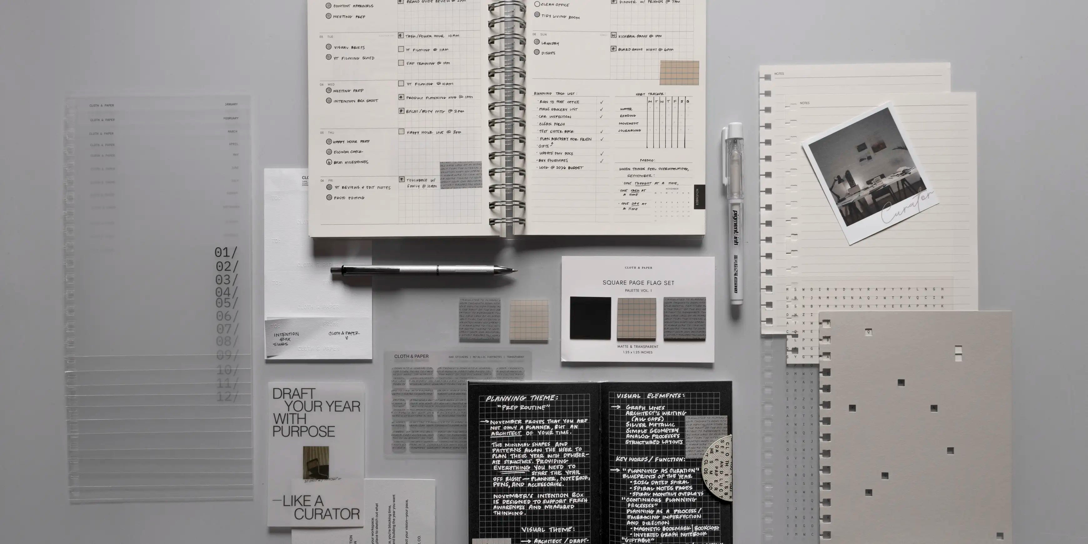 Collection of stationery items including a 2026 Spiral Notebook, pen and planner stickers on a light gray surface.