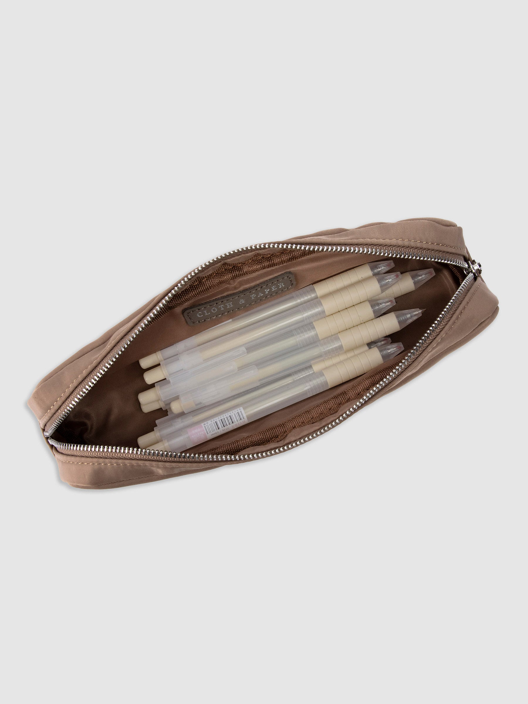 Closeup of Cloth and Paper logo inside of pencil pouch. A selection of Tombow brush pens are stored inside the pouch. Color featured is fossil.