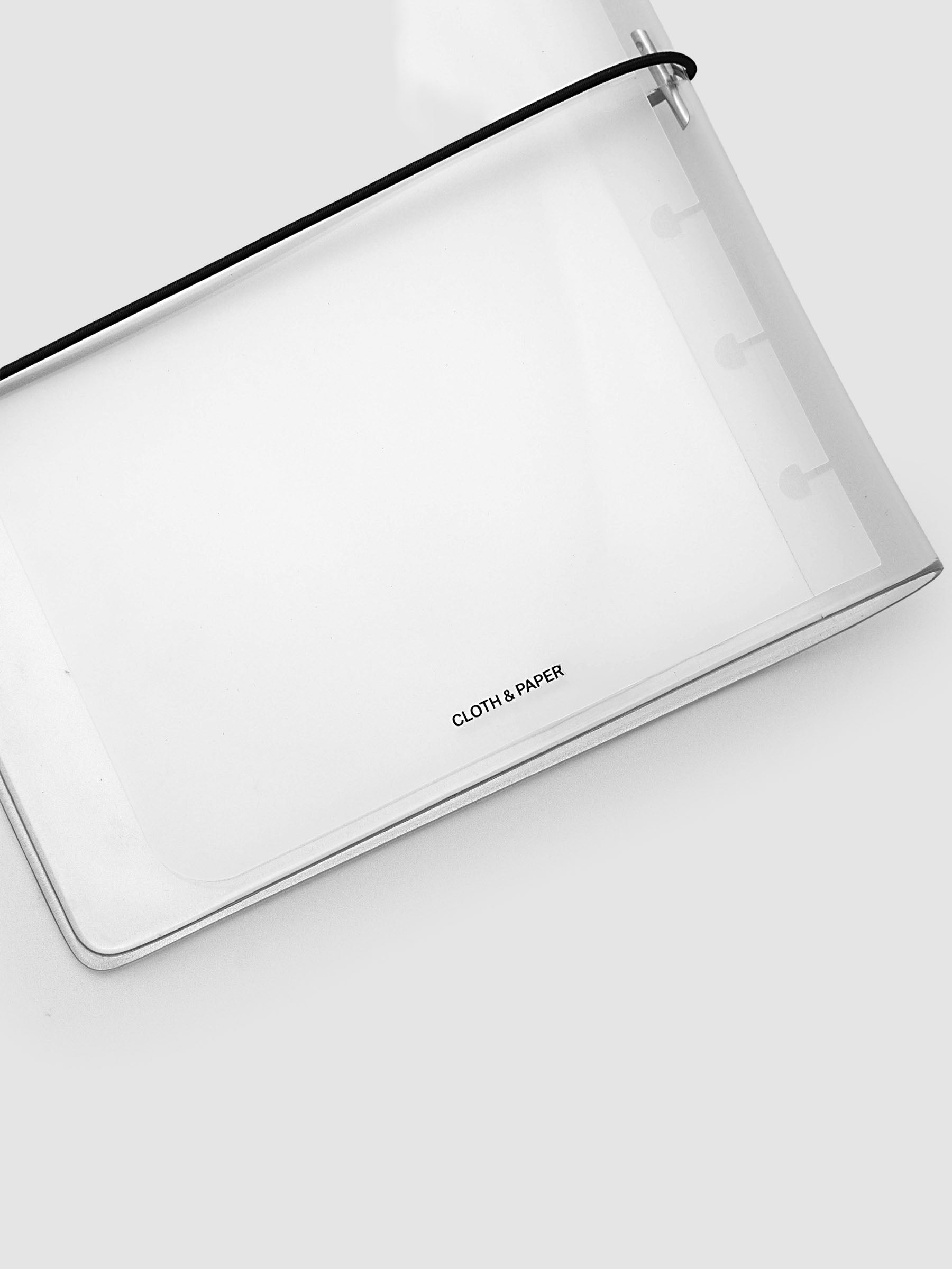 A clear plastic cover with a black elastic band closure, featuring the text 'CLOTH & PAPER' printed in black near the bottom, shot on a light gray background.