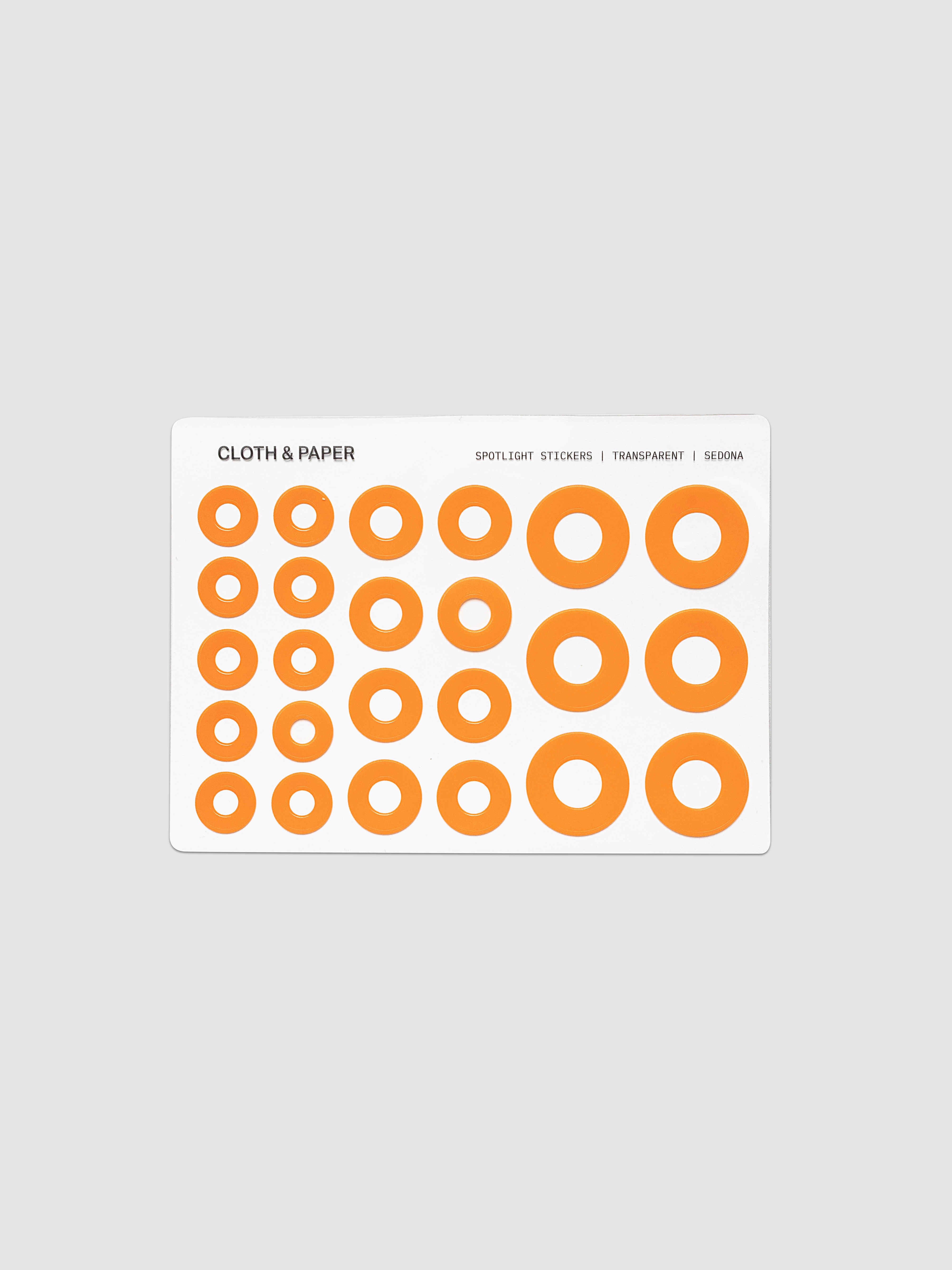 One sheet of circular stickers in varying sizes, featuring a bright orange ring design on a white backing card, set against a solid light gray background.