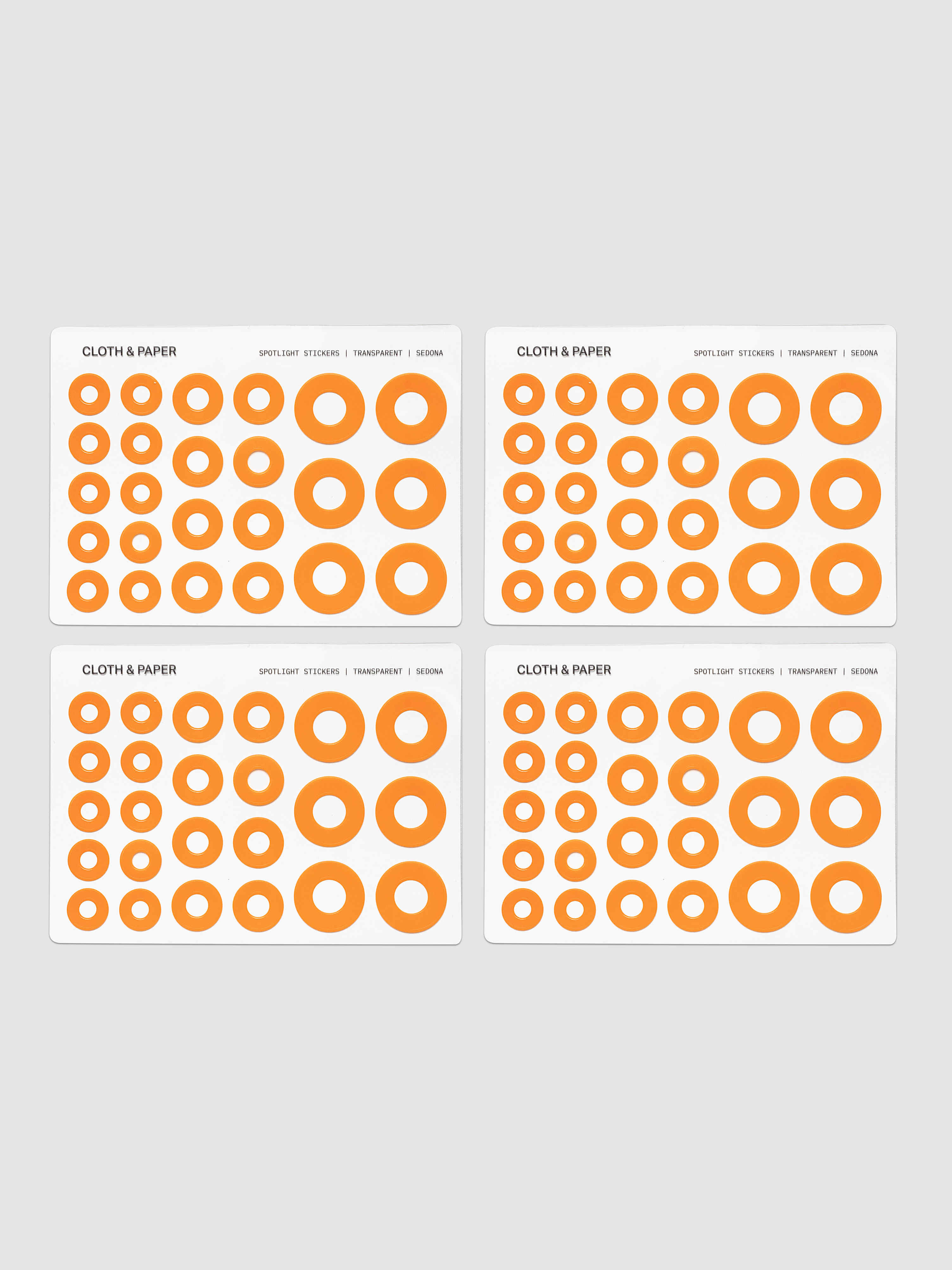 Four sheets of circular stickers of various sizes in a bright orange, arranged on a light gray background.