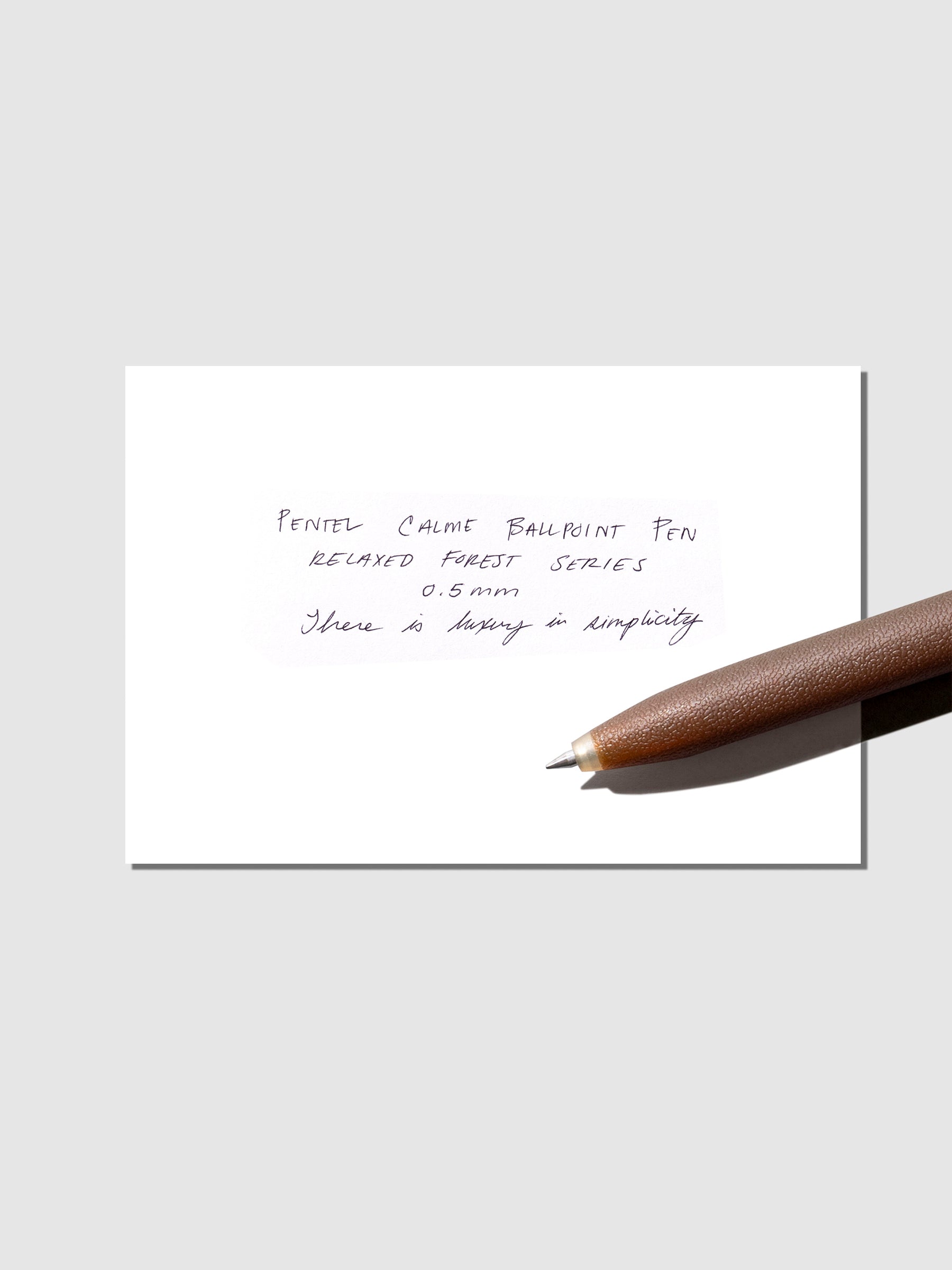 Pen test sheet shown with brown pen on a neutral background.