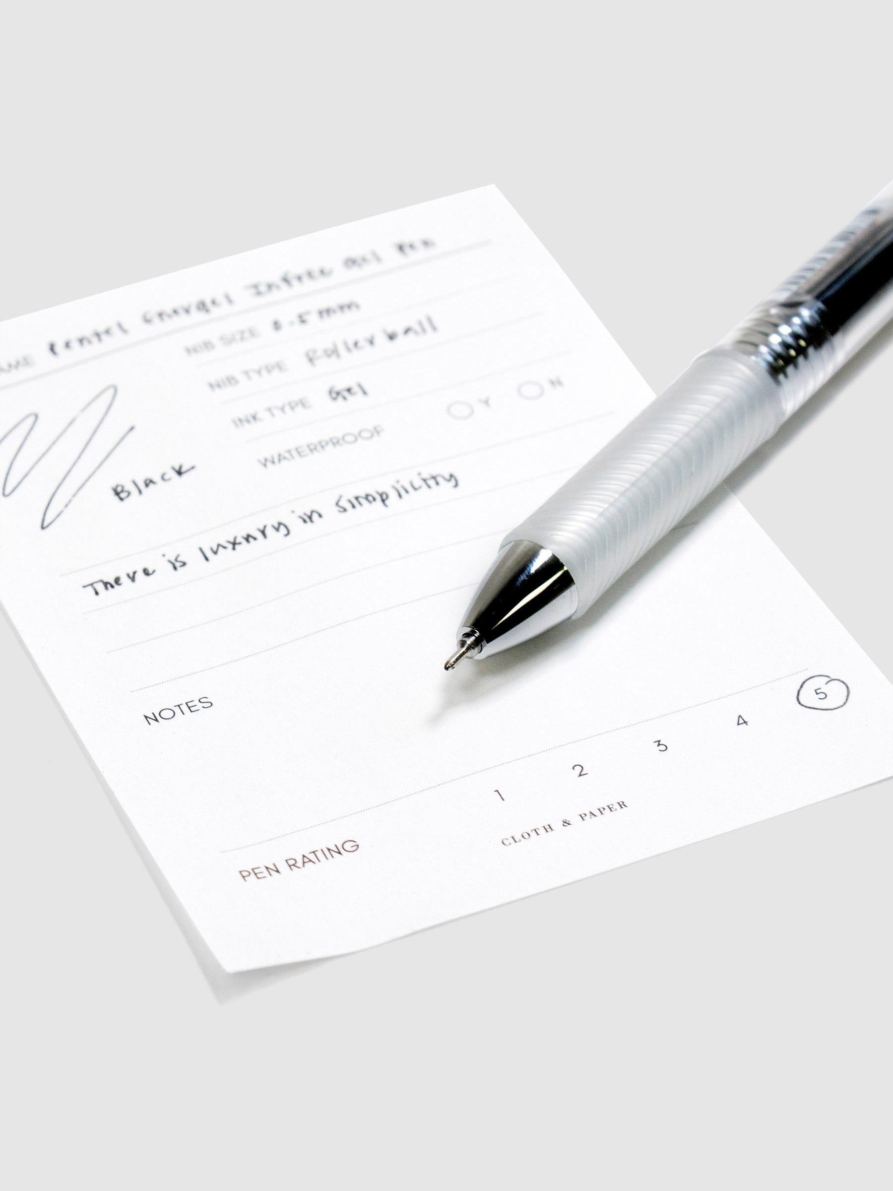 Pentel Energel Infree Gel Pen, Black, Cloth and Paper. Close up on pen nib resting on pen test sheet.