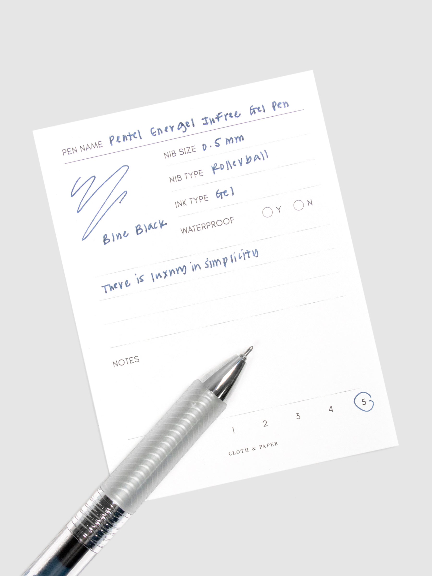 Pentel Energel Infree Gel Pen, Blue-Black, Cloth and Paper. Pen resting on pen test sheet displaying writing sample.